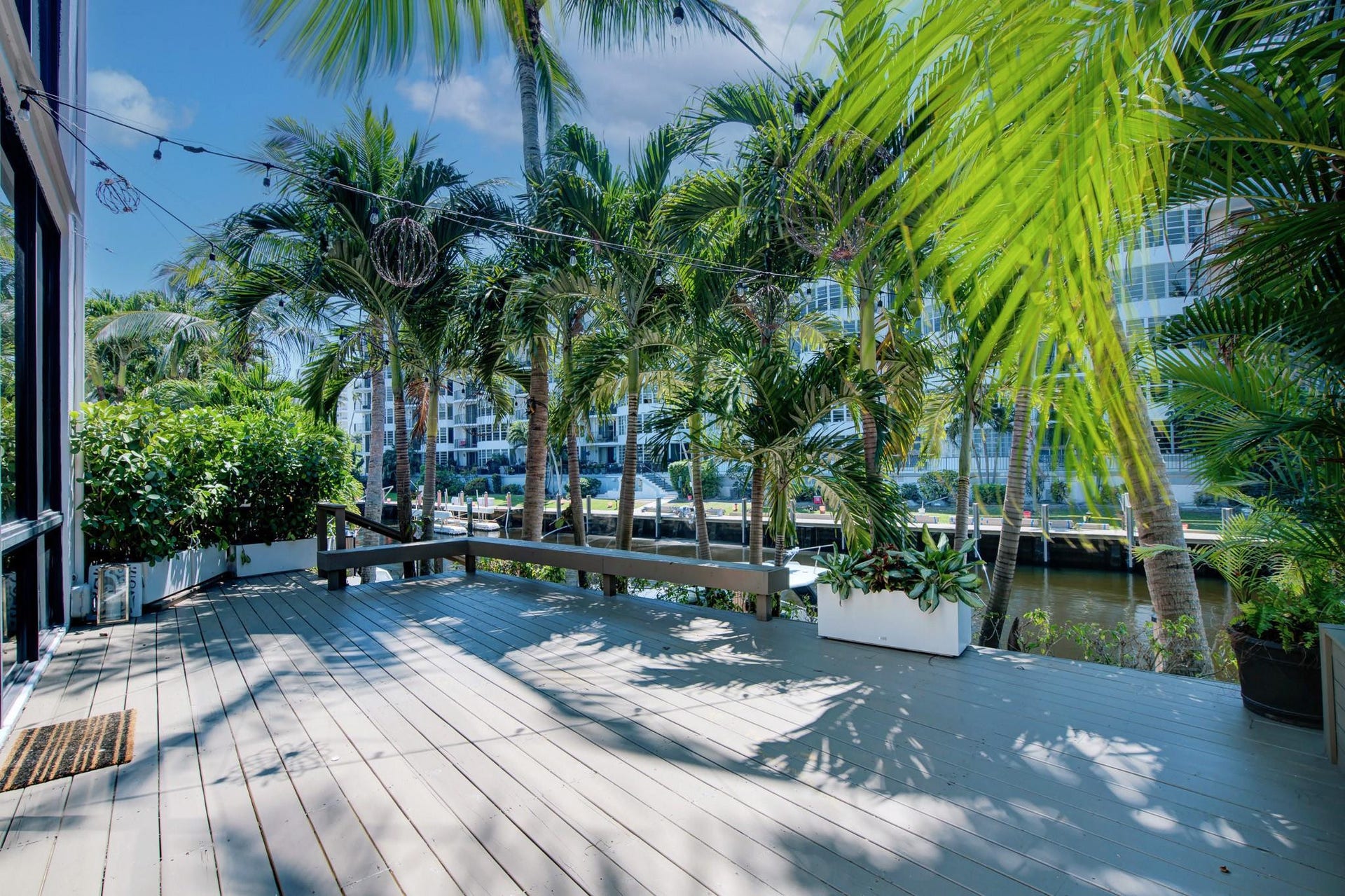 Expansive outdoor deck with a built-in bench, surrounded by mature palm trees and lush landscaping