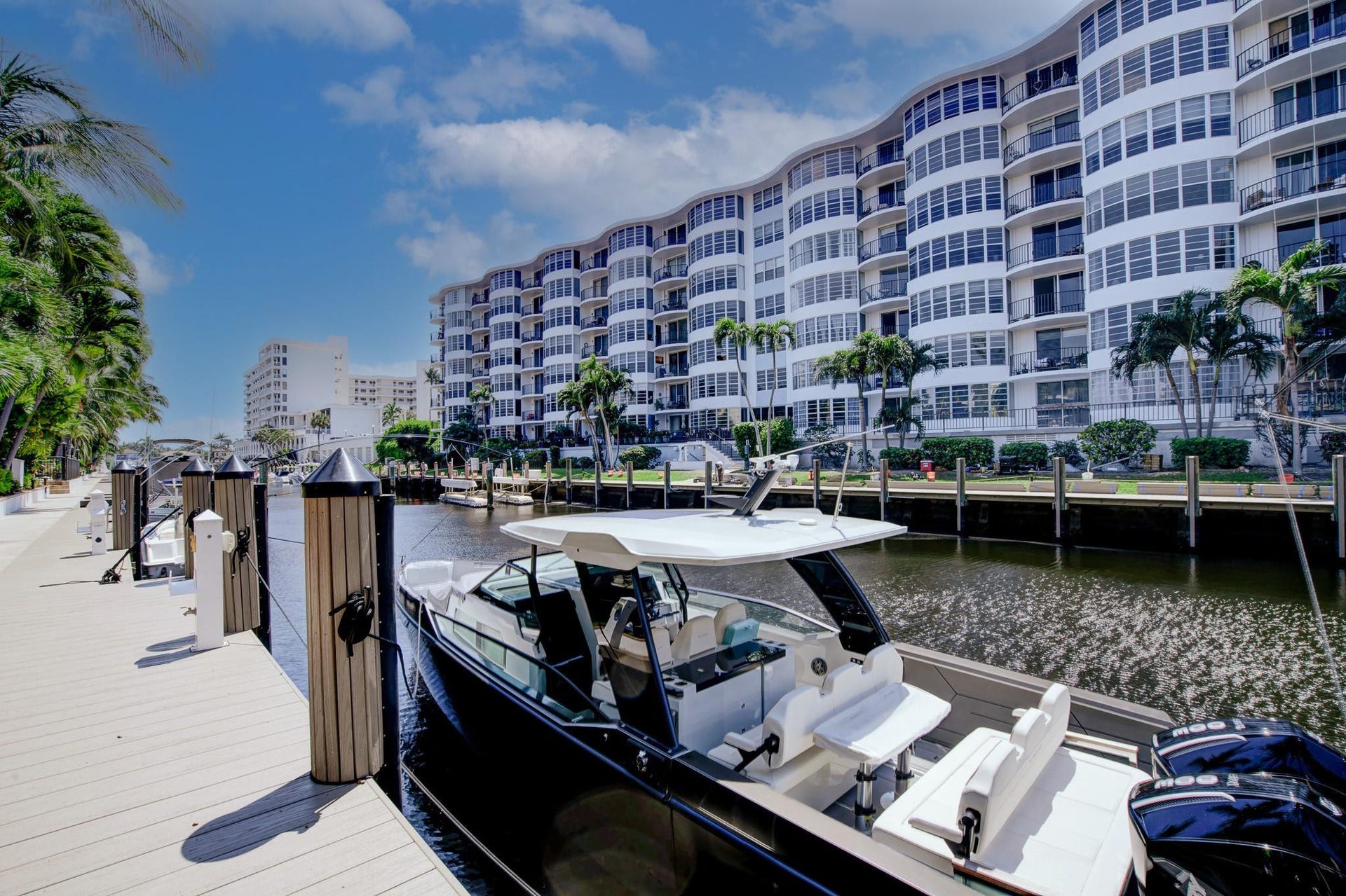 Waterfront property with a multi-story building featuring extensive balcony space, an expansive dock area, and lush tropical landscaping