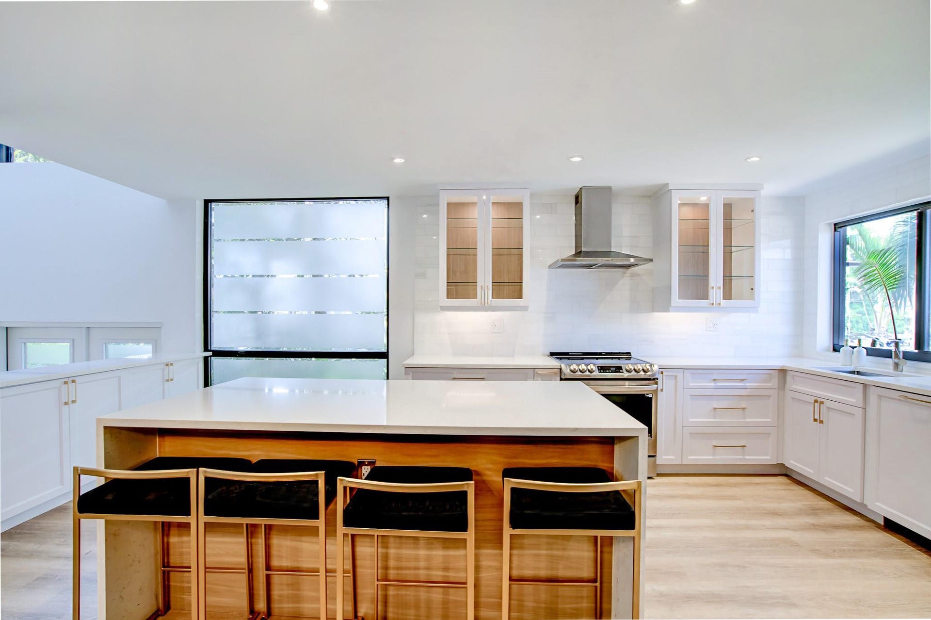 Kitchen featuring a large central island, white cabinetry, stainless steel range with hood, and light wood-finish flooring