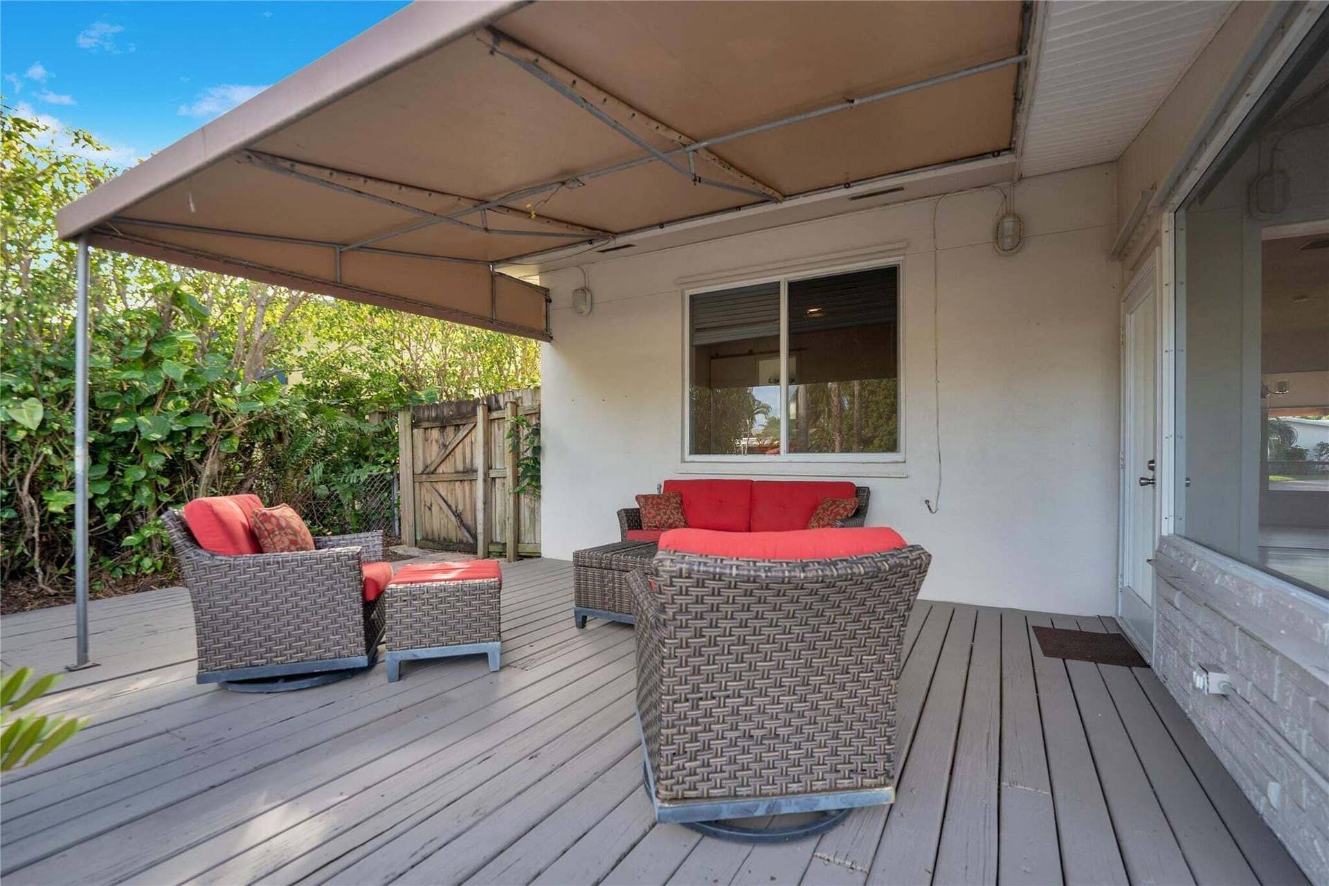 2142 NE 17th Avenue, Wilton Manors, FL 33305 Virtually staged. Covered outdoor patio featuring a wood-finish deck and mature landscaping