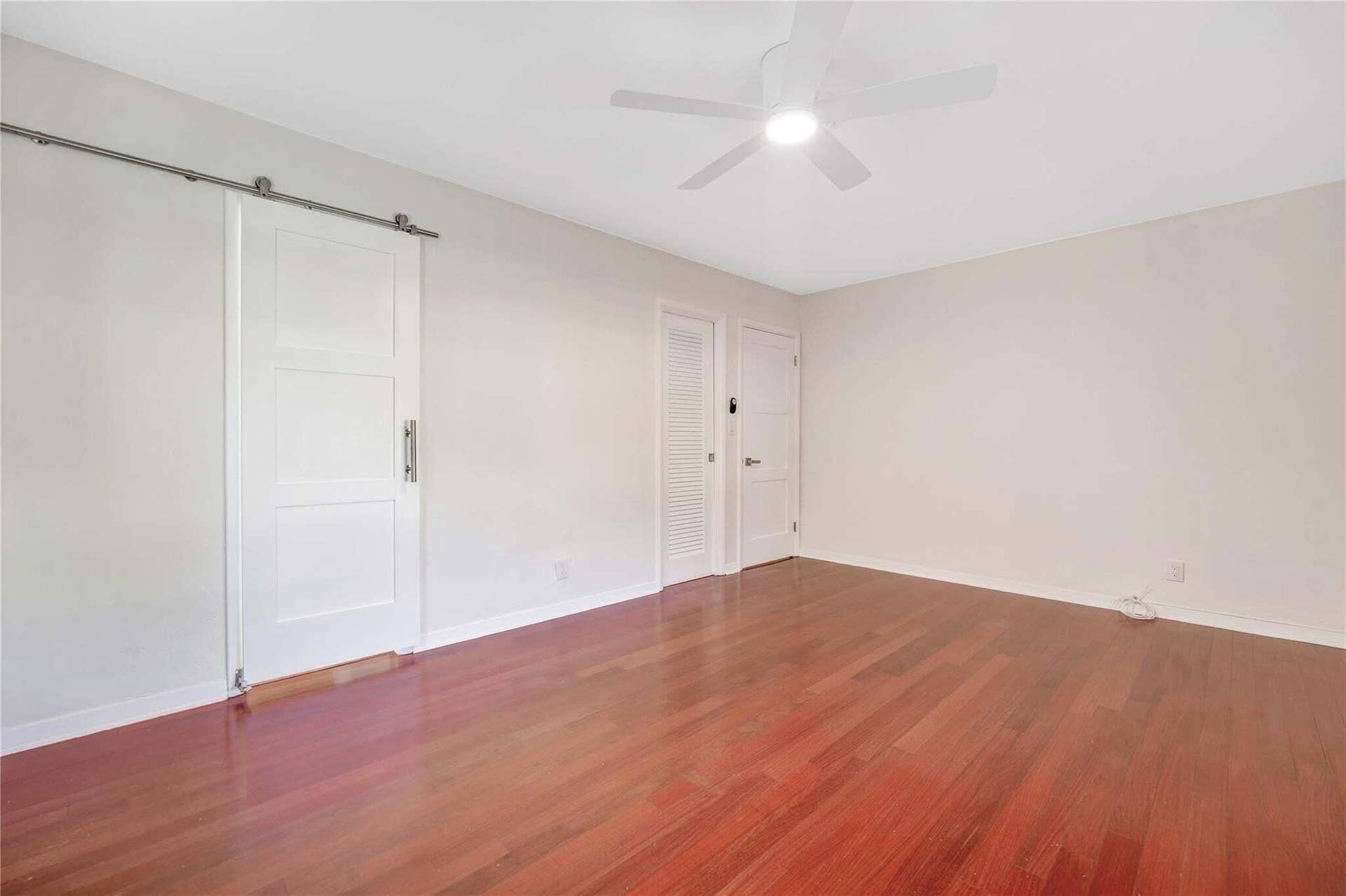 2142 NE 17th Avenue, Wilton Manors, FL 33305 Rich wood-finish flooring, white walls, and a ceiling fan with integrated lighting