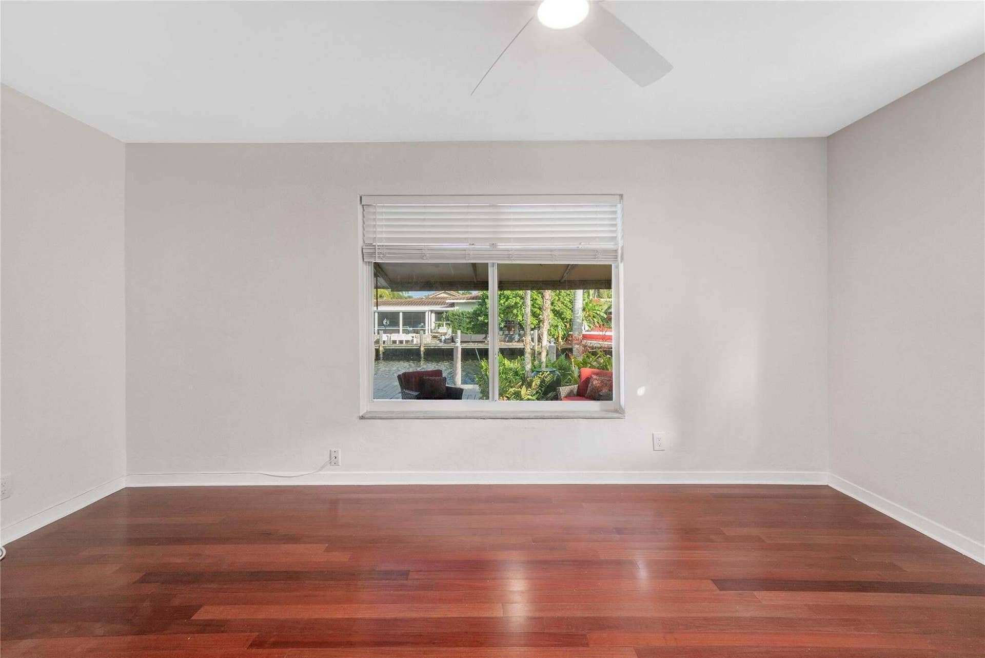 2142 NE 17th Avenue, Wilton Manors, FL 33305 Wood-finish flooring with a window offering canal views, featuring a ceiling fan and horizontal blinds
