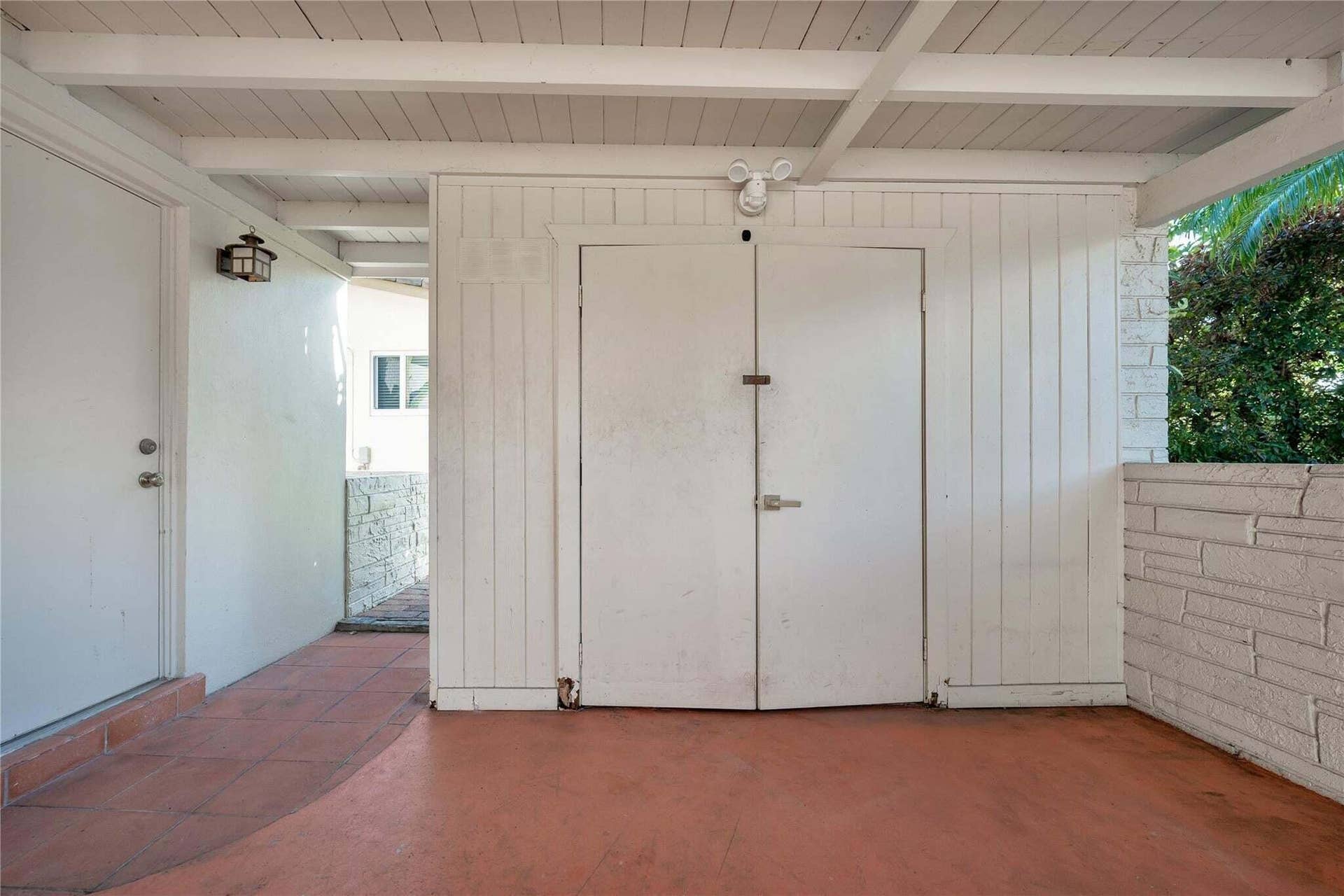 2142 NE 17th Avenue, Wilton Manors, FL 33305 Covered outdoor area with terracotta-toned flooring, white exposed beam ceiling, and a white paneled storage unit