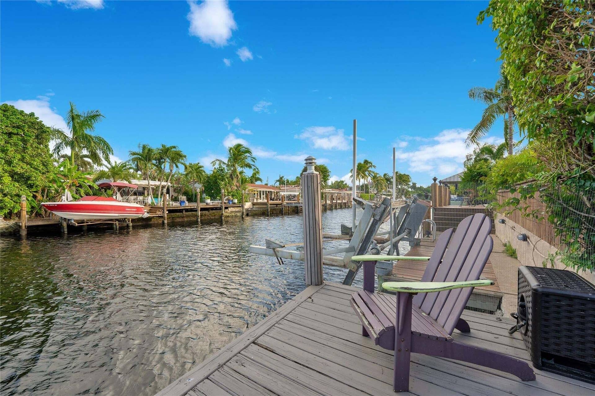 2142 NE 17th Avenue, Wilton Manors, FL 33305 Waterfront property featuring a wood-plank dock, boat lift, and mature palm trees