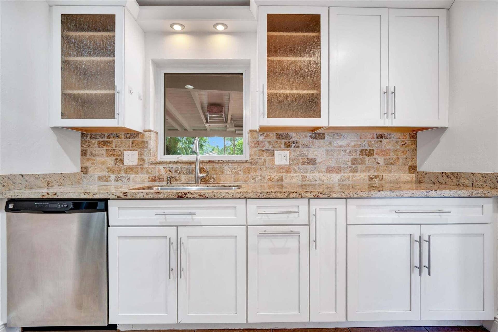 2142 NE 17th Avenue, Wilton Manors, FL 33305 White shaker-style cabinetry with stainless steel hardware, granite countertops, and a brick-patterned tile backsplash