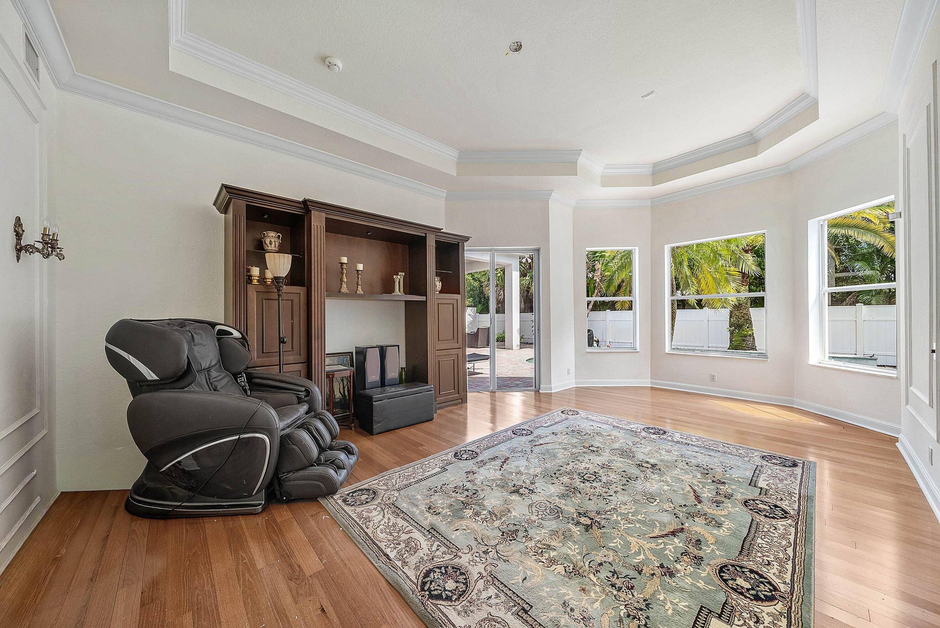 Tray ceiling with crown molding, wood-finish flooring, and a slider door leading to pool/outdoor area