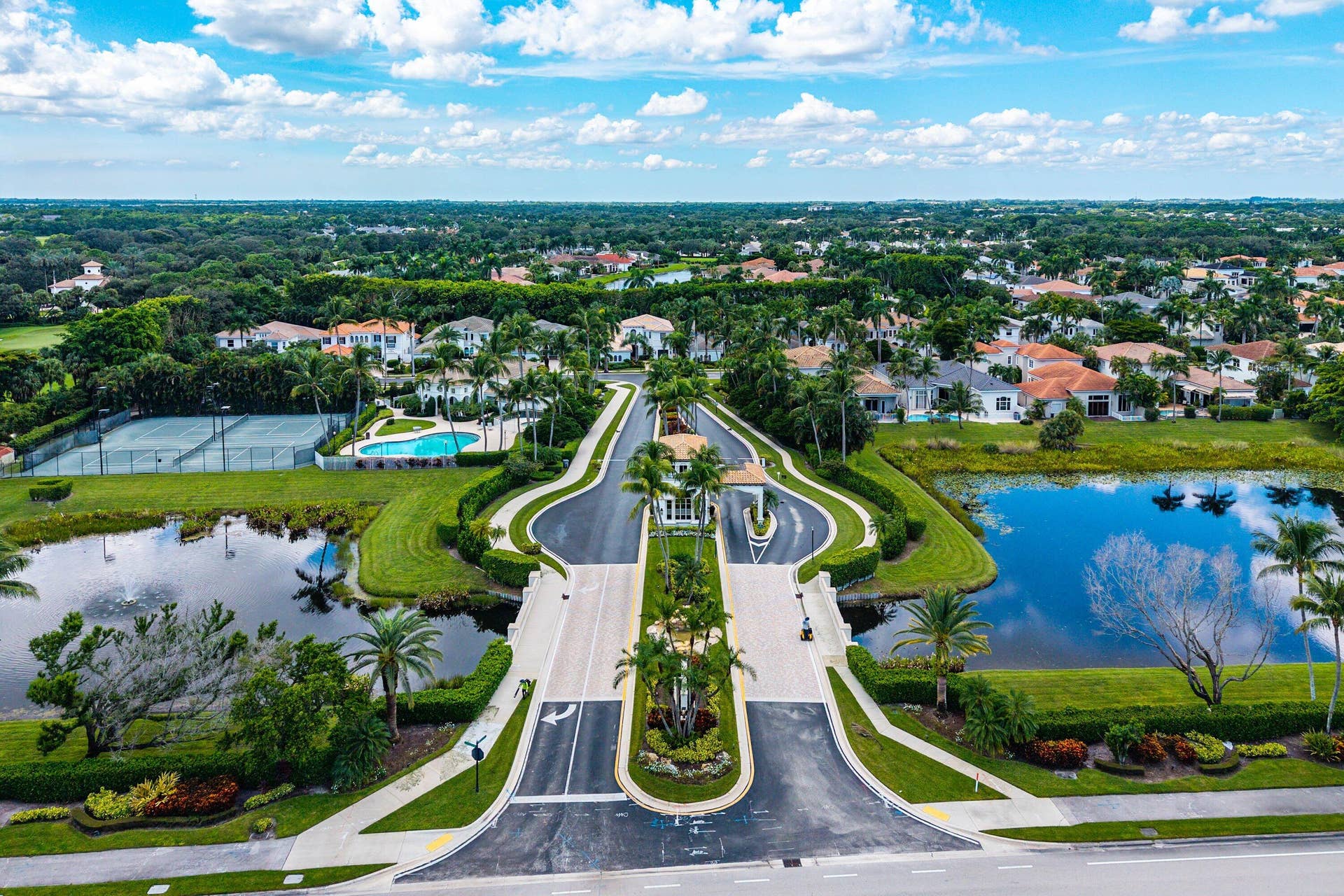 Gated community (24/7 manned) entrance with surrounding water features, and lush landscaping