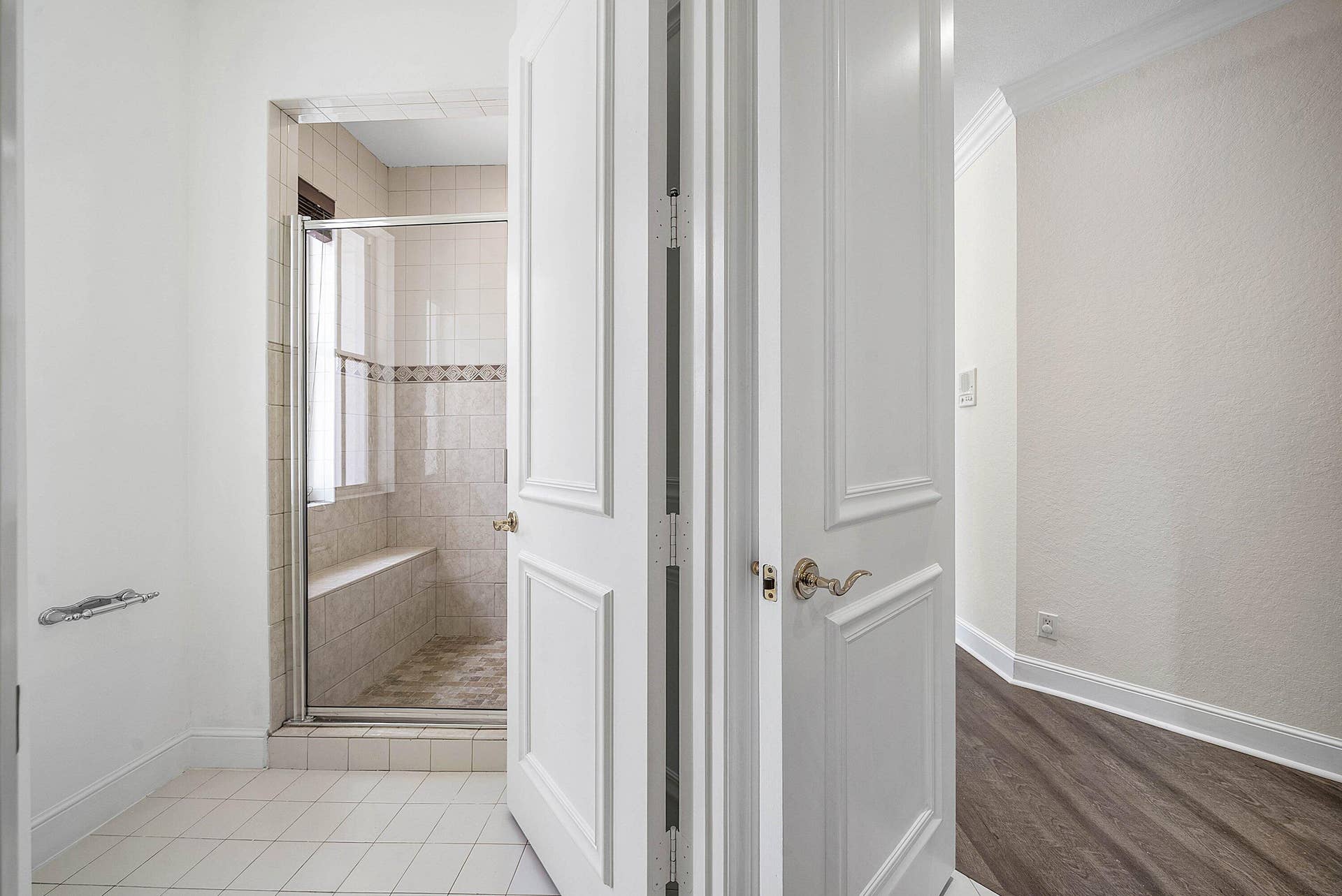 Shower enclosure with a glass door, built-in bench, and tile surround