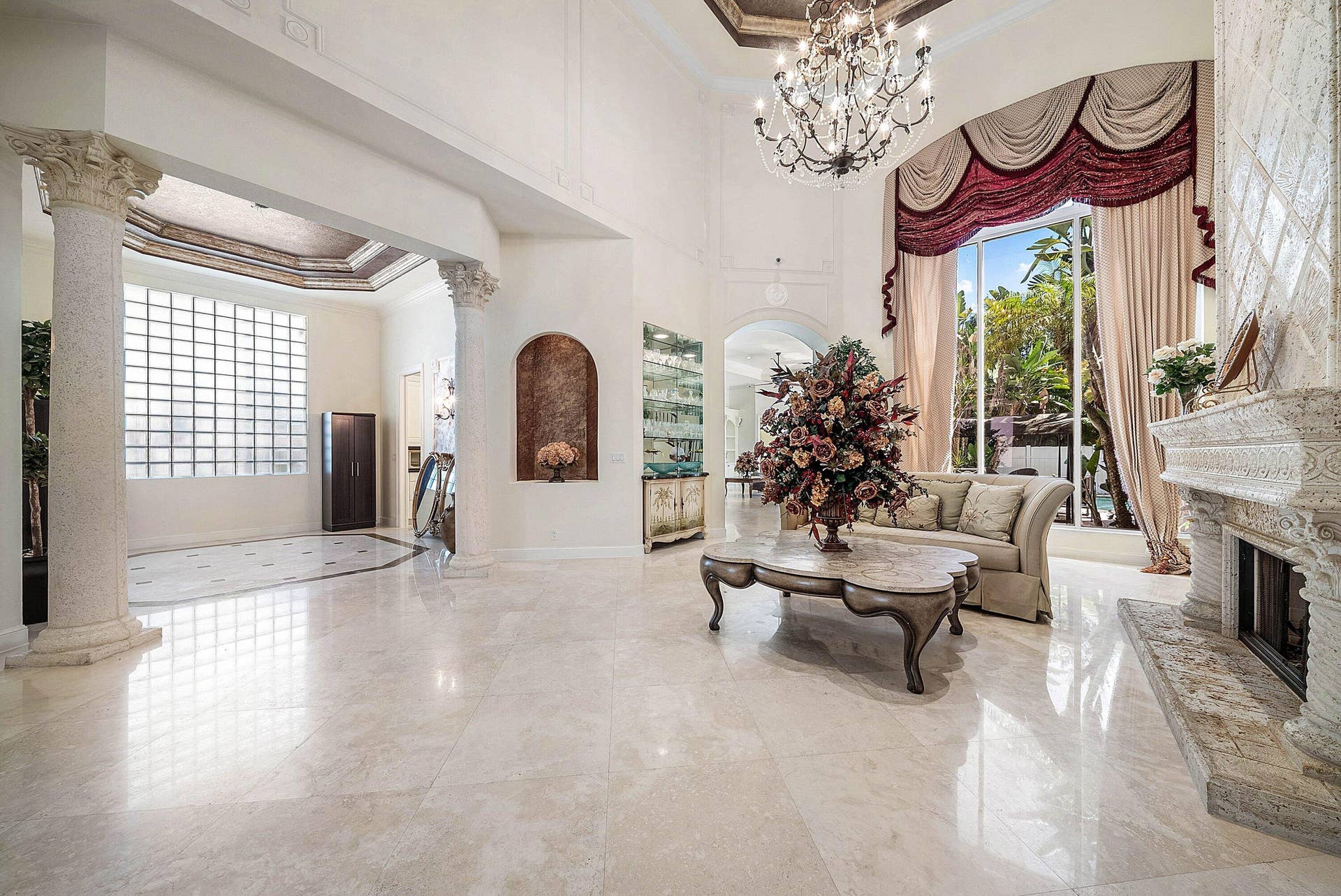 Soaring ceilings, polished marble flooring, stone fireplace, decorative columns.