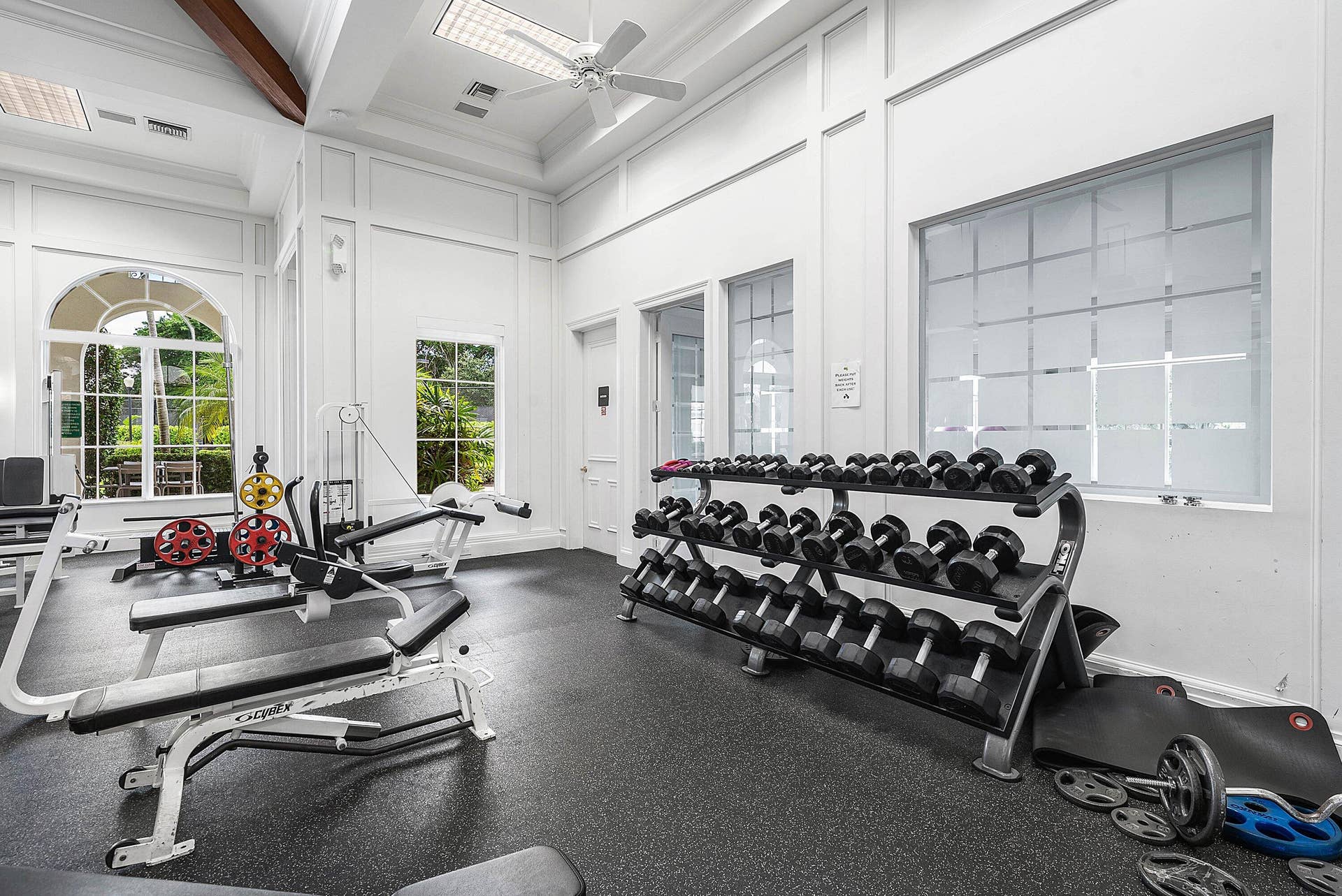 Fitness facility with high vaulted ceilings, architectural wall paneling, large arched windows, and rubberized flooring