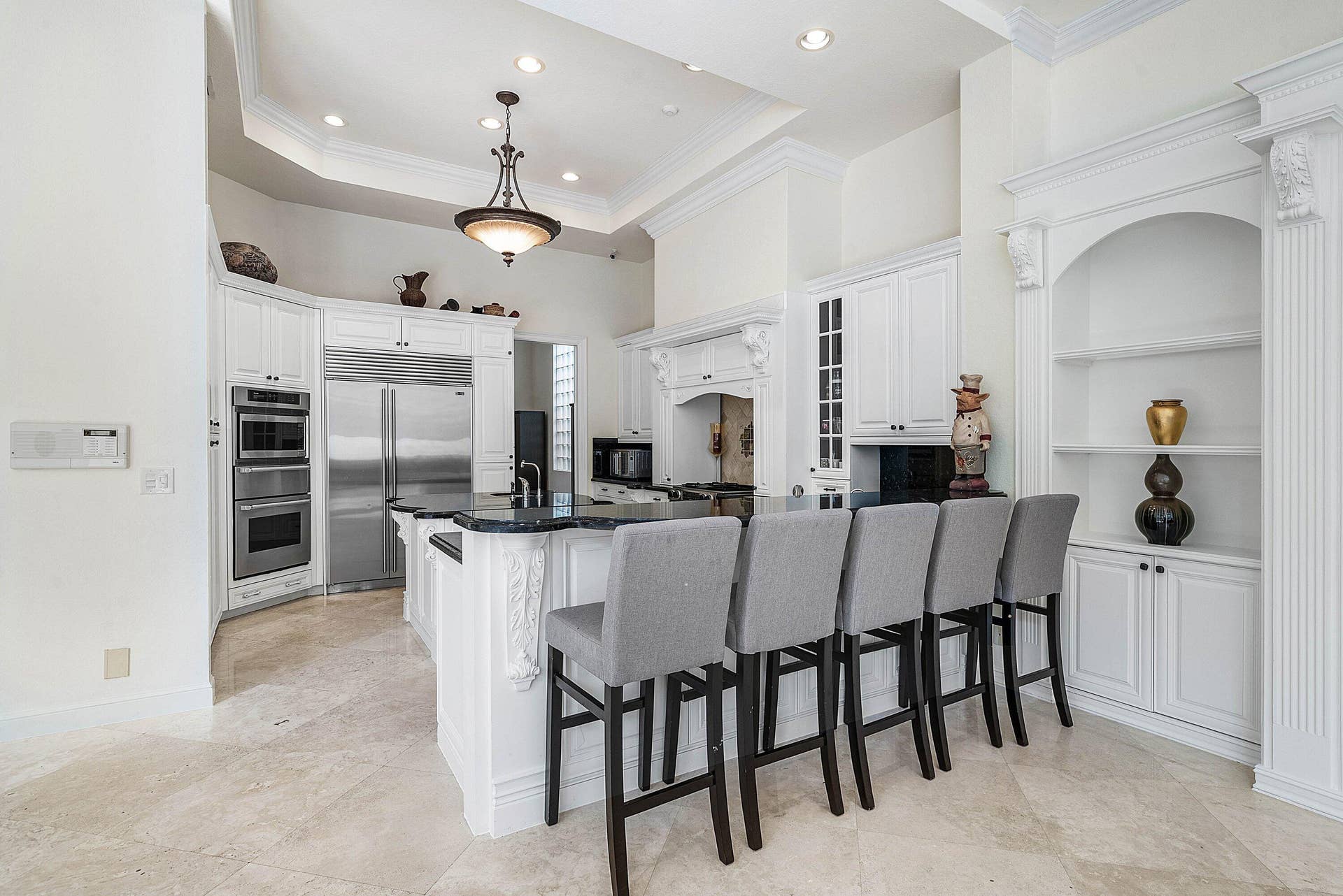 Gourmet kitchen with stainless steel appliances, white cabinetry, granite countertops, a large island with seating, and recessed lighting