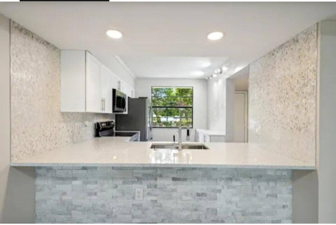 Beautiful White kitchen w/ stone wall decor