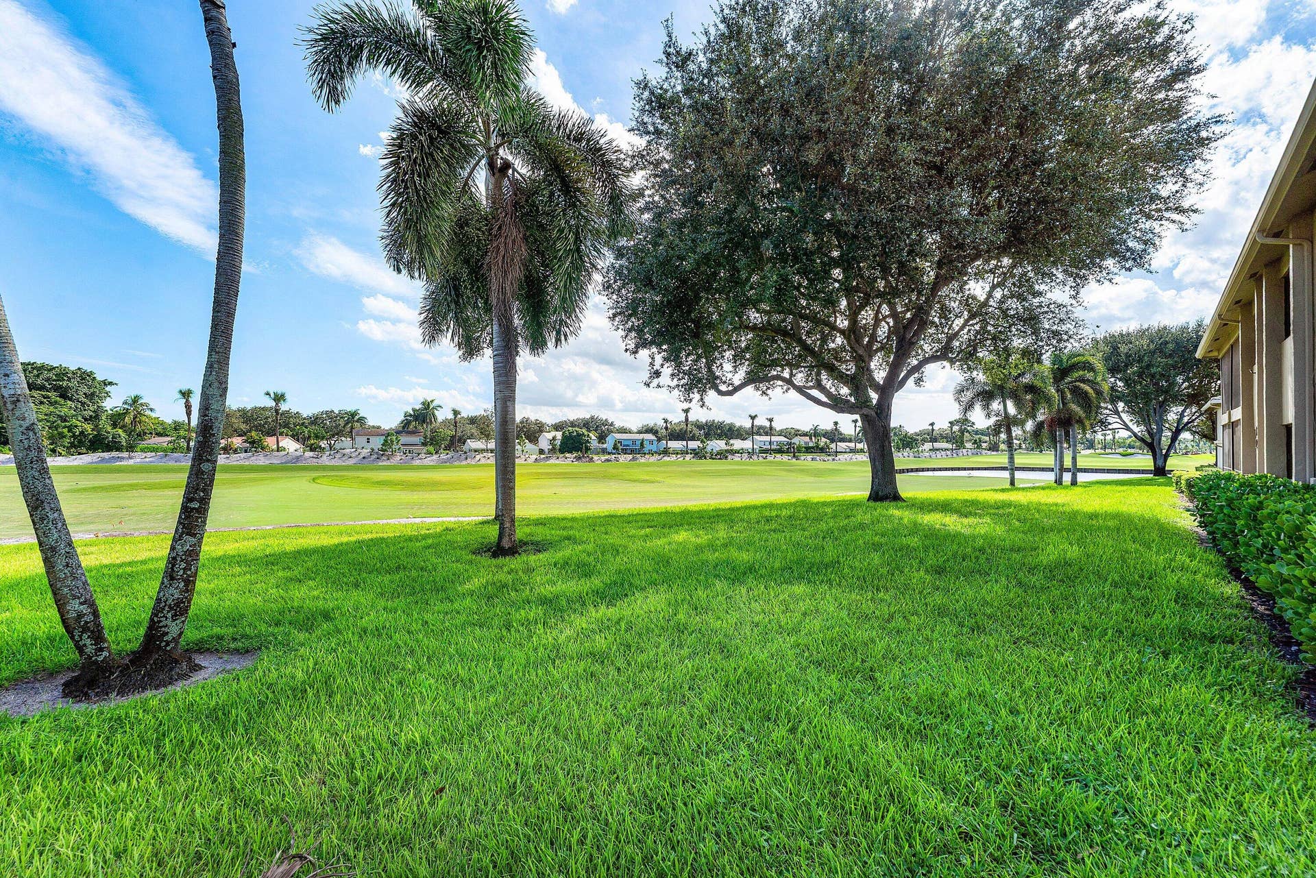 12 Stratford Drive E, #A, Boynton Beach, FL 33436 Expansive green space with manicured lawn, mature trees, palm trees, and established shrubbery