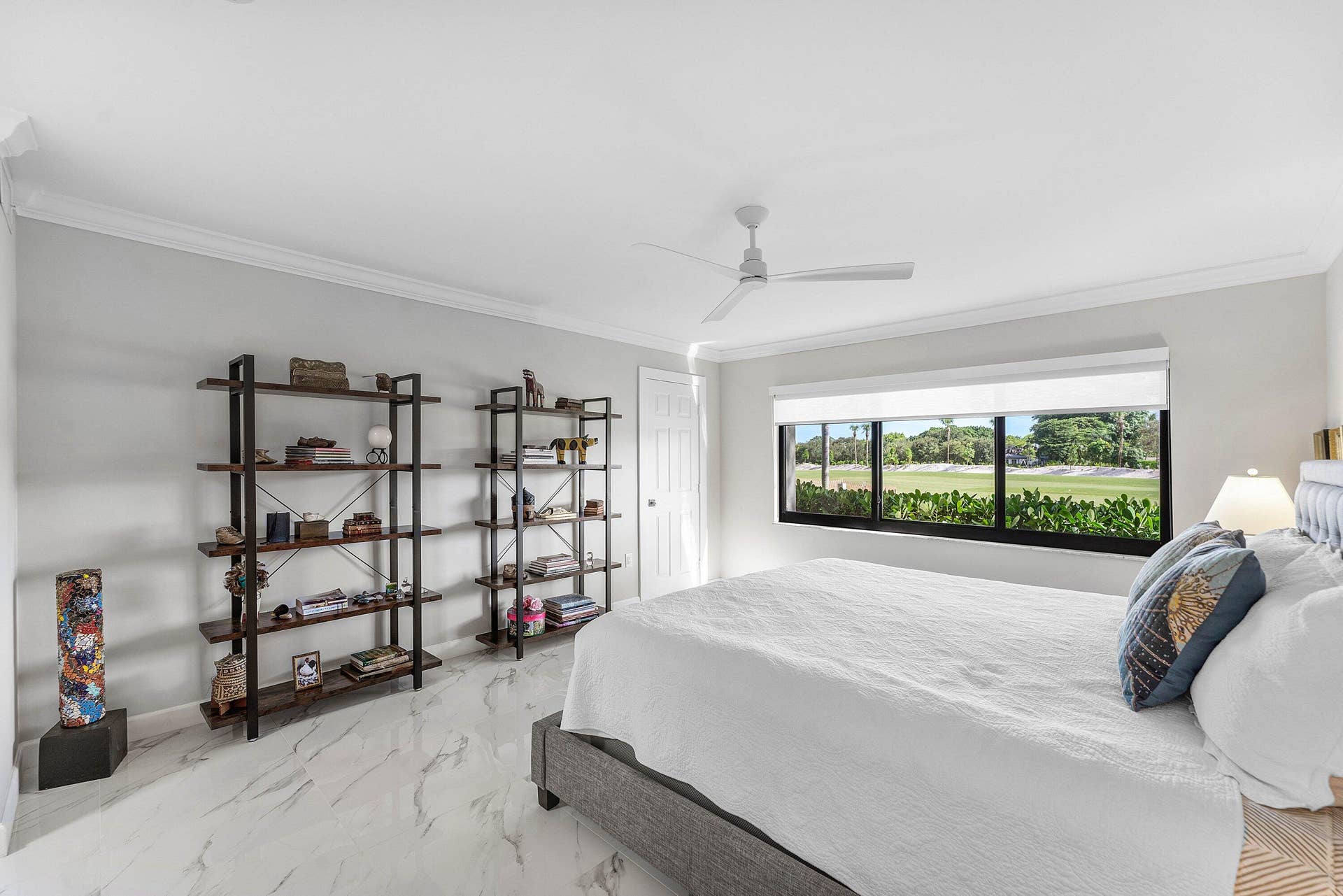 12 Stratford Drive E, #A, Boynton Beach, FL 33436 White marble-look flooring, crown molding, a ceiling fan, and a wide window with exterior landscaping