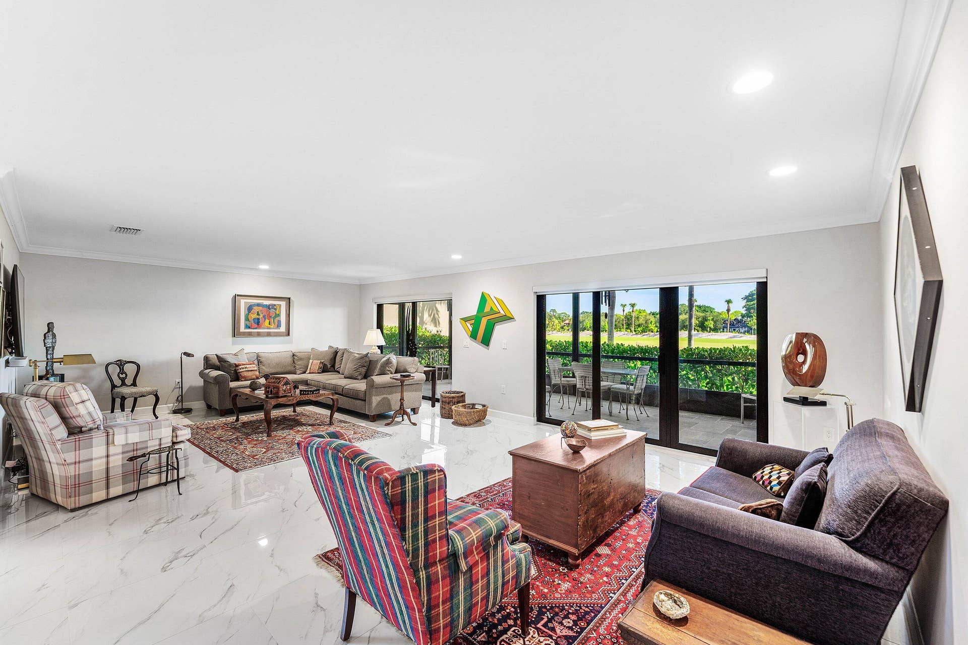 12 Stratford Drive E, #A, Boynton Beach, FL 33436 White tile flooring, recessed lighting, crown molding, and glass sliding doors leading to an outdoor patio with a concrete surface