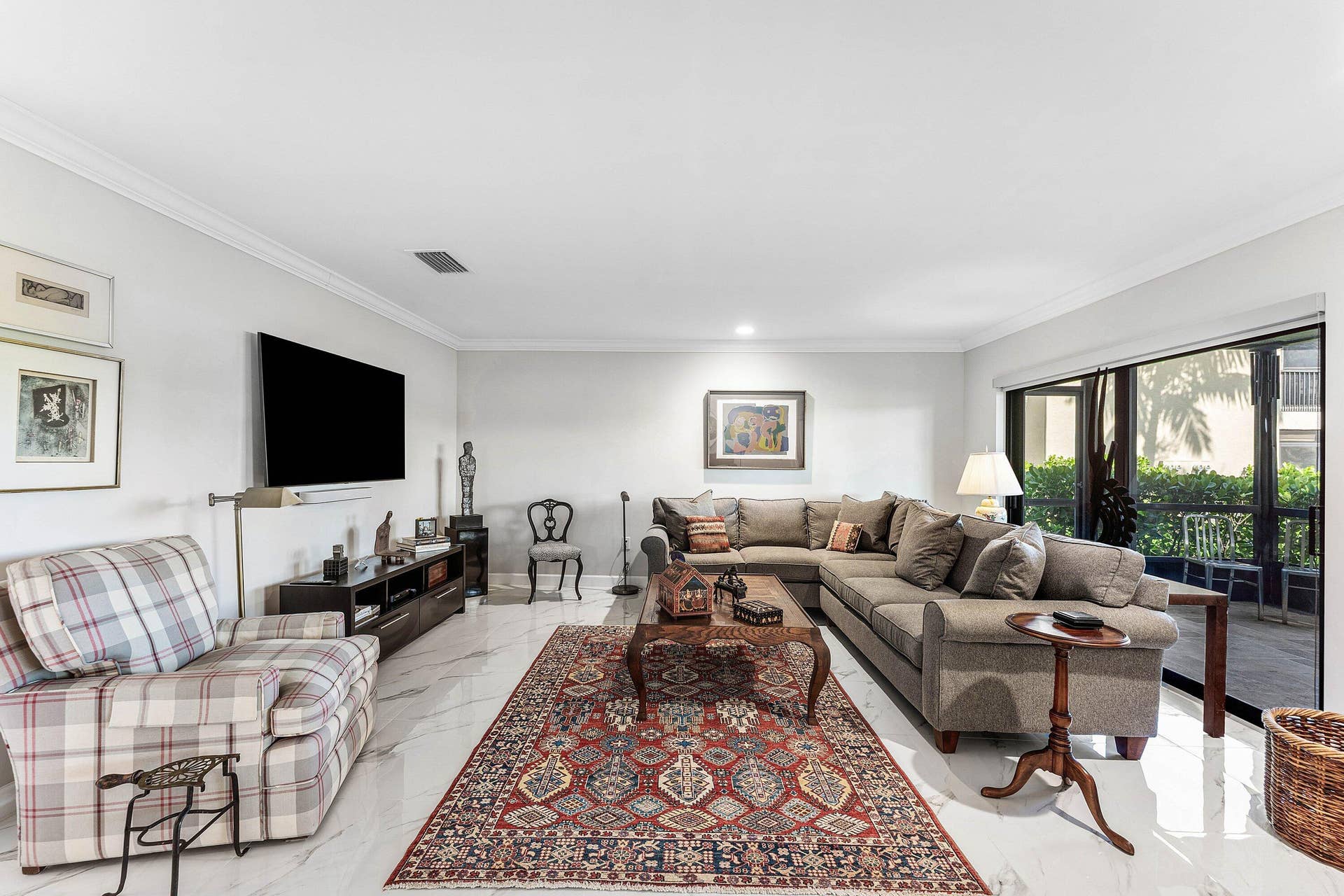 12 Stratford Drive E, #A, Boynton Beach, FL 33436 Spacious living area featuring white tile flooring, crown molding, and sliding glass doors