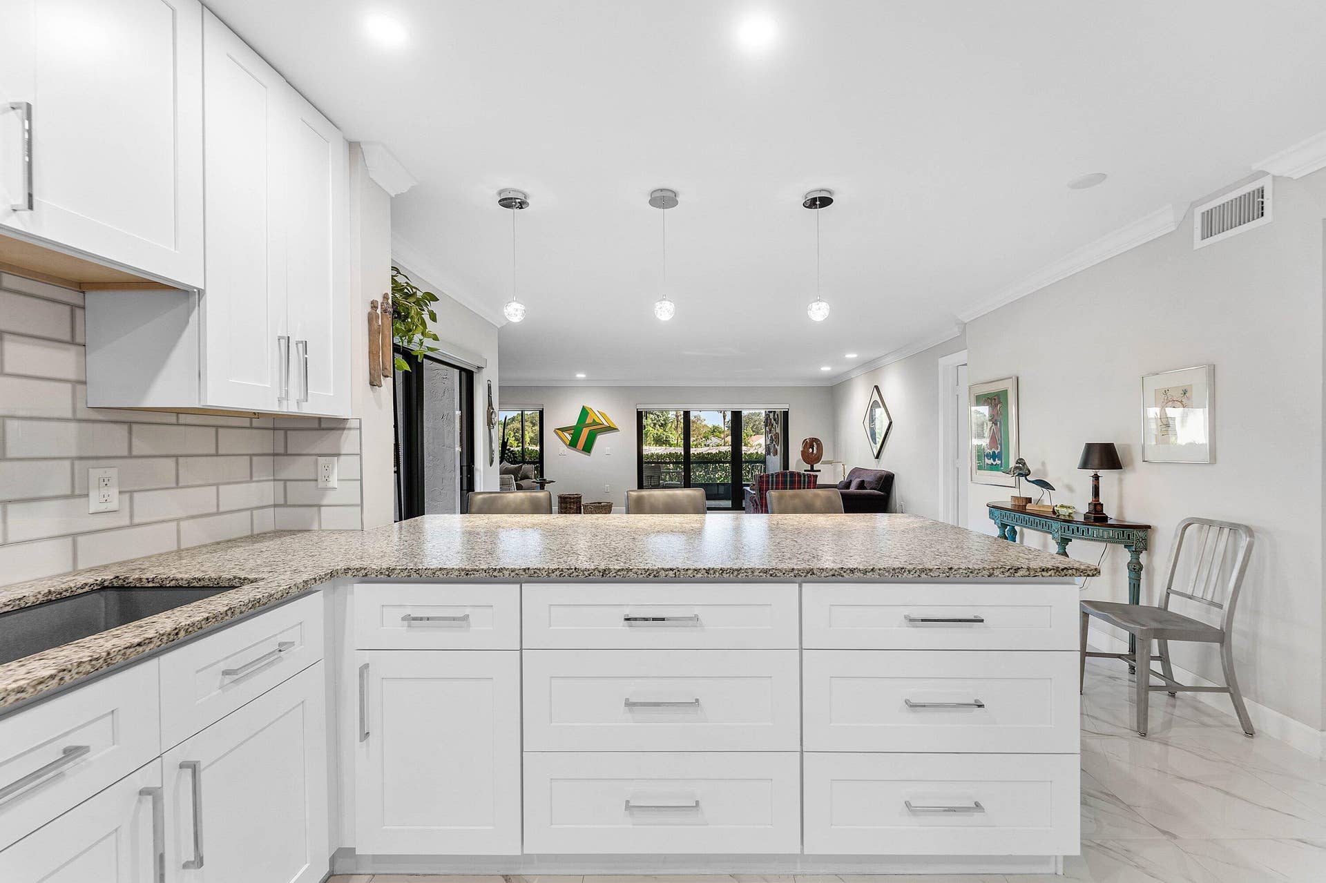 12 Stratford Drive E, #A, Boynton Beach, FL 33436 Kitchen featuring white shaker cabinetry, speckled countertops, subway tile backsplash, recessed lighting, and a kitchen island with pendant lighting
