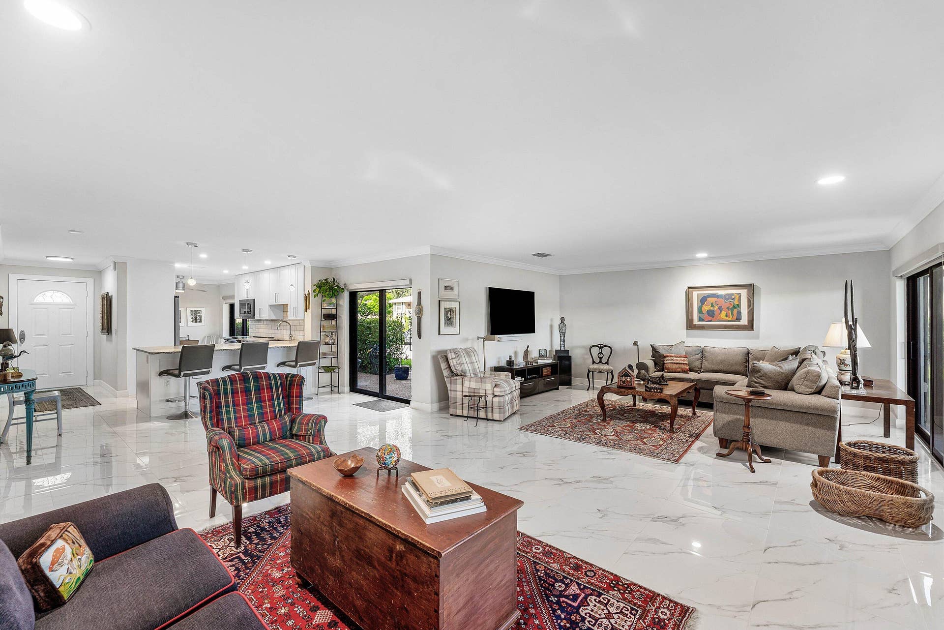 12 Stratford Drive E, #A, Boynton Beach, FL 33436 Spacious open-concept living area featuring polished tile flooring, recessed lighting, crown molding, and a sliding glass door