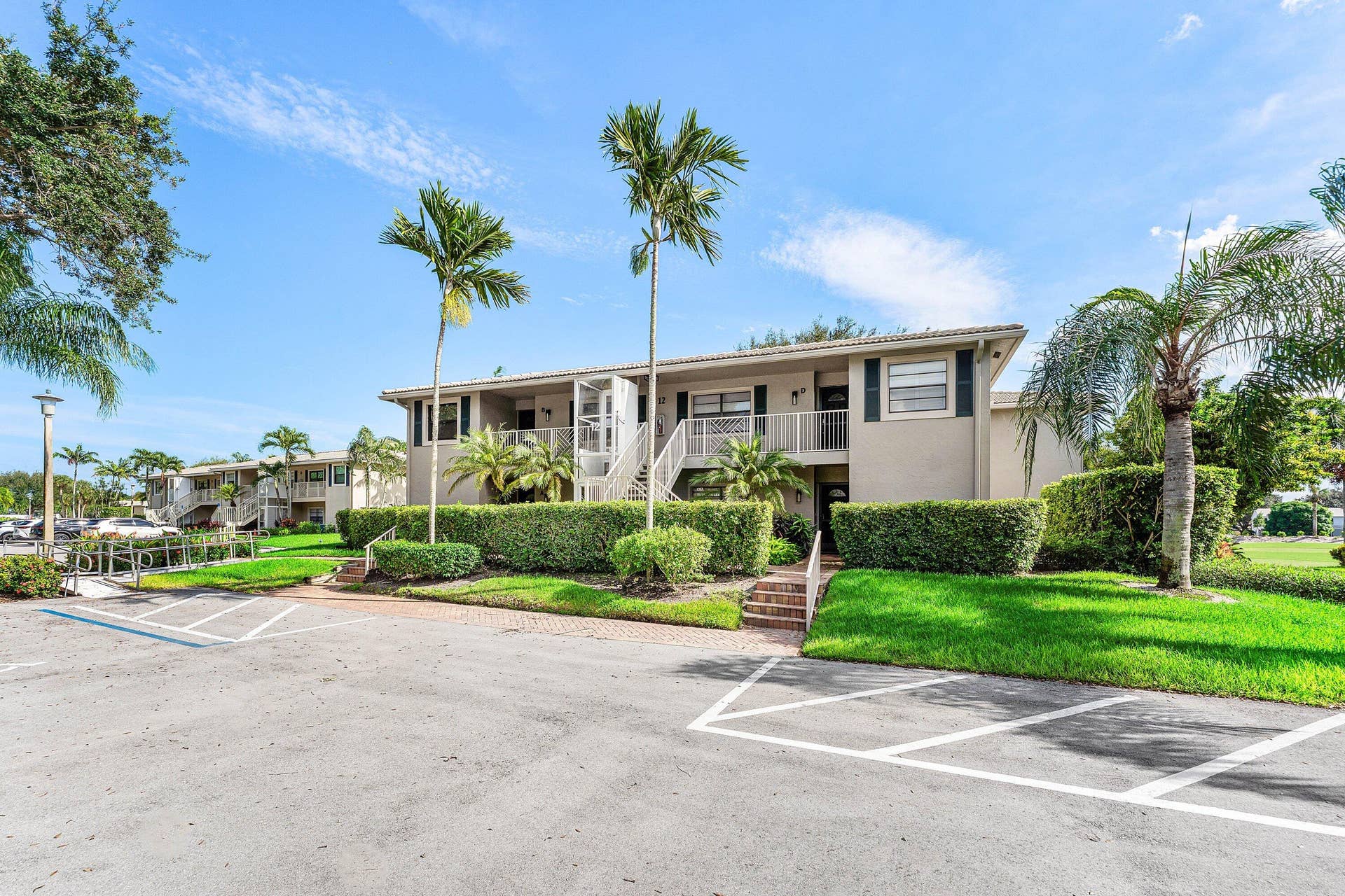 12 Stratford Drive E, #A, Boynton Beach, FL 33436 Exterior featuring multiple residential units, balconies, and lush landscaping