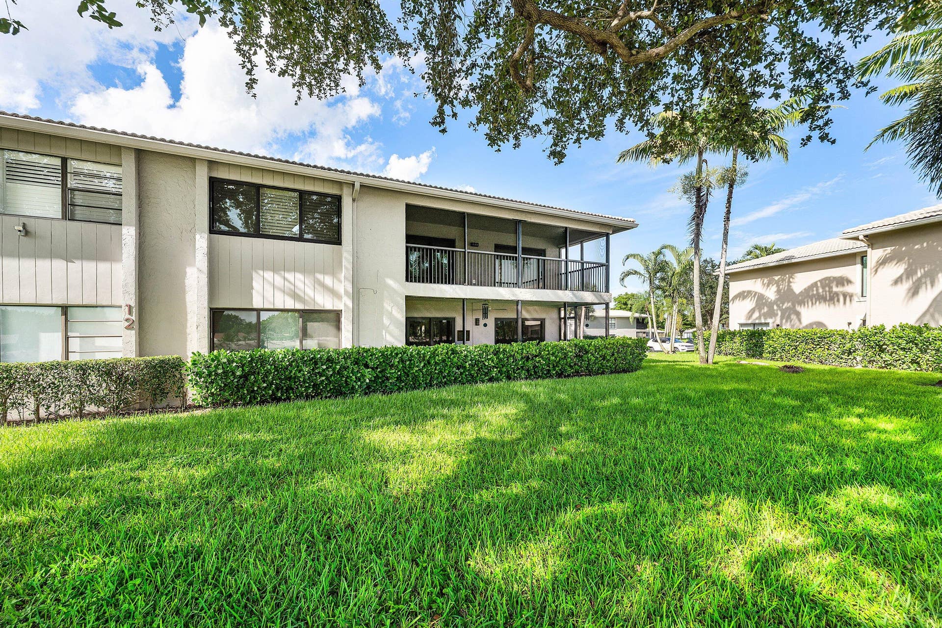 12 Stratford Drive E, #A, Boynton Beach, FL 33436 Manicured lawn with dense green hedging and mature trees