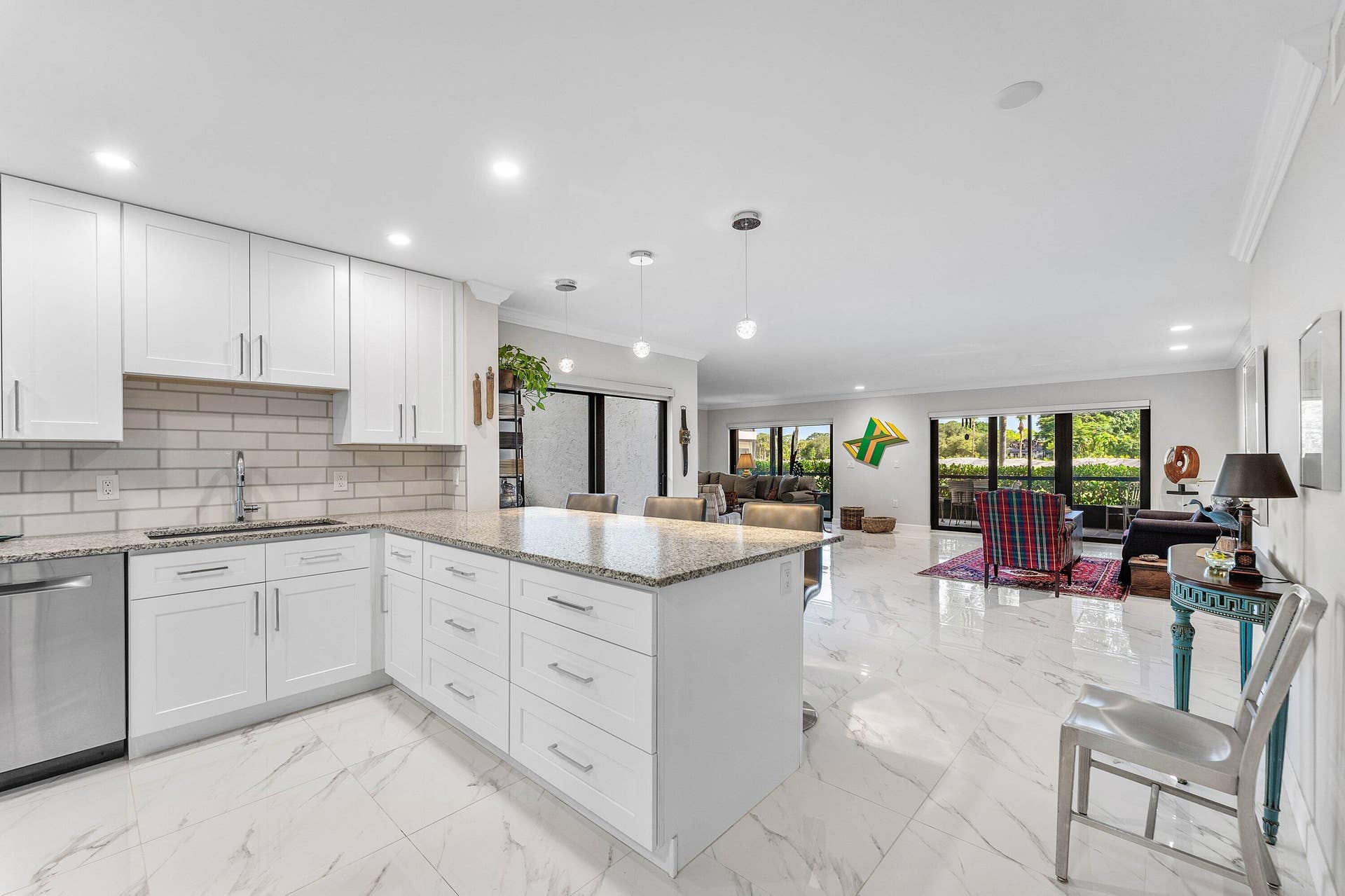 12 Stratford Drive E, #A, Boynton Beach, FL 33436 Updated kitchen featuring white shaker cabinetry, stainless steel dishwasher, and a center island with pendant lighting