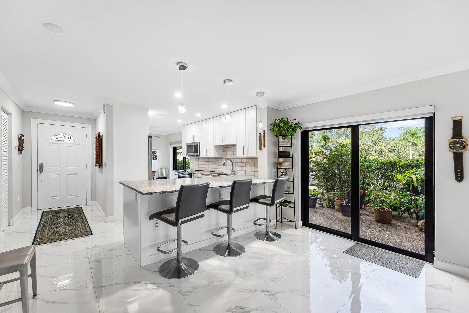 12 Stratford Drive E, #A, Boynton Beach, FL 33436 Gleaming white tile flooring, kitchen island with seating, pendant lighting, built-in cabinetry, and sliding glass doors to outdoor space