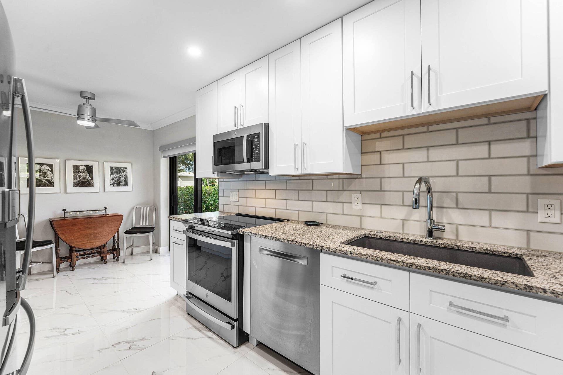 12 Stratford Drive E, #A, Boynton Beach, FL 33436 Kitchen featuring white cabinetry, stainless steel appliances, granite countertops, and a subway tile backsplash