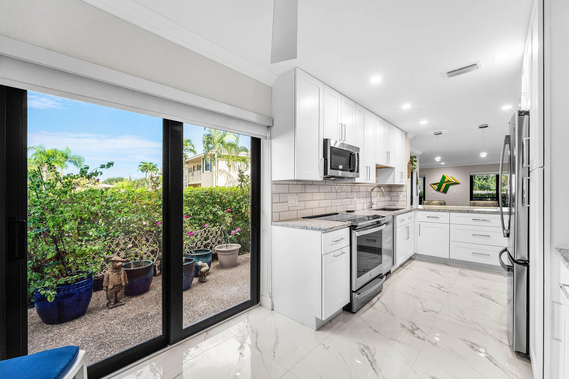 12 Stratford Drive E, #A, Boynton Beach, FL 33436 Modern kitchen featuring white cabinetry, stainless steel appliances, light-toned granite countertops, and a subway tile backsplash