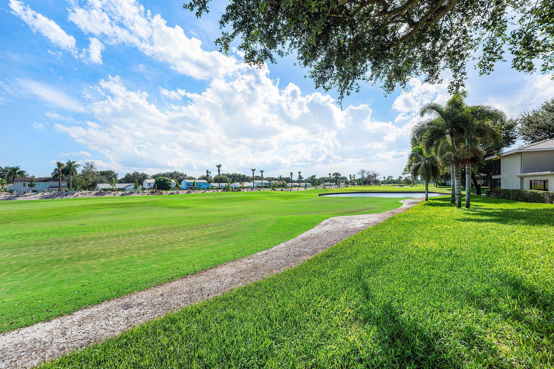 12 Stratford Drive E, #A, Boynton Beach, FL 33436 Expansive green space featuring a water element, mature palm trees, and a visible building structure