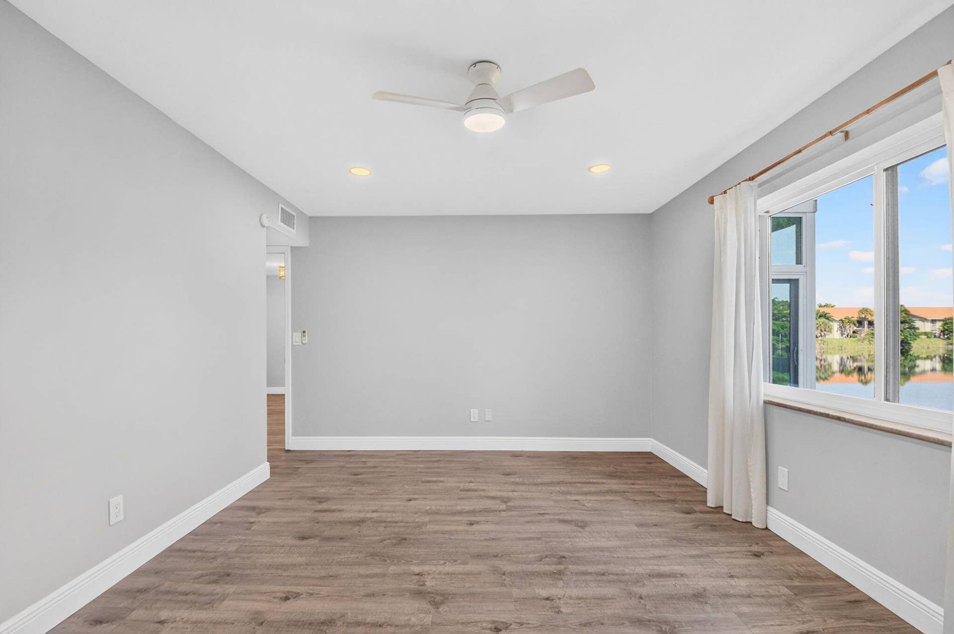 163 LAKE EVELYN Drive, West Palm Beach, FL 33411 Primary Bedroom w Lake View, Impact Window, New Ceiling Fan, New Window Treatments