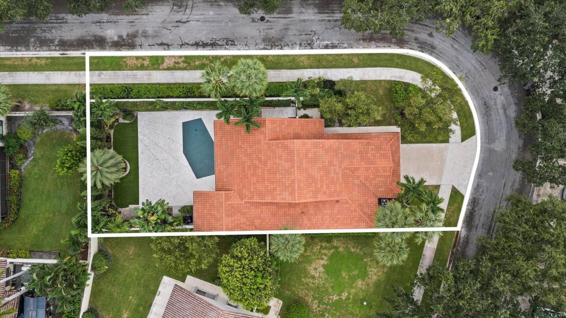 2890 ANTIETAM Lane, West Palm Beach, FL 33409 Mediterranean-style roofline, geometric swimming pool, paved patio, mature landscaping, and an expansive driveway