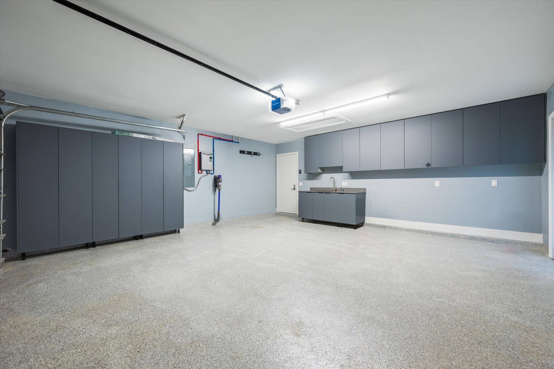 2890 ANTIETAM Lane, West Palm Beach, FL 33409 Expansive garage featuring a speckled epoxy floor, extensive built-in storage cabinetry, a utility sink, and overhead fluorescent lighting