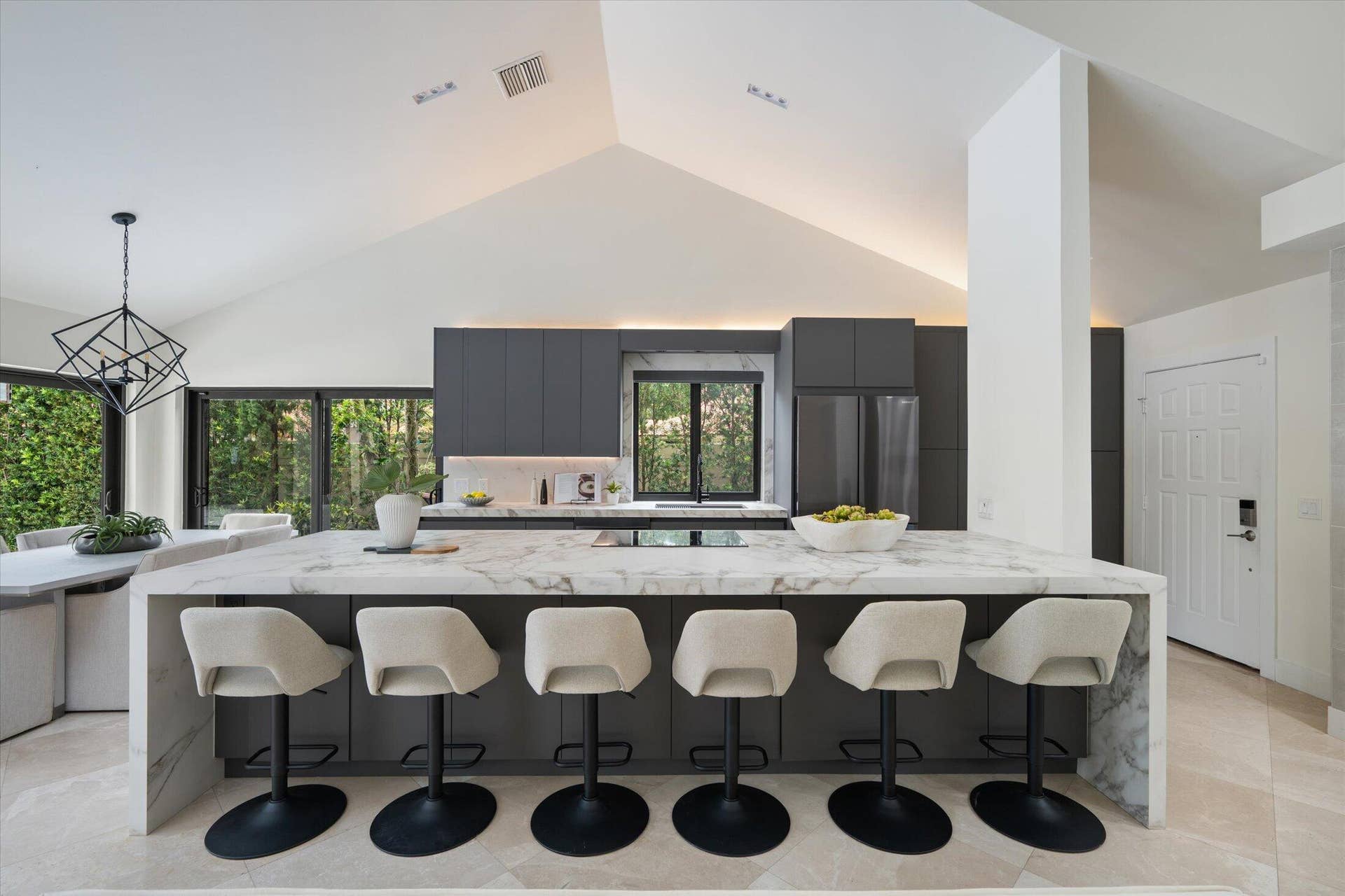 2890 ANTIETAM Lane, West Palm Beach, FL 33409 Vaulted ceiling with accent lighting, large kitchen island with waterfall edge, cabinetry, stainless steel appliances, and large windows