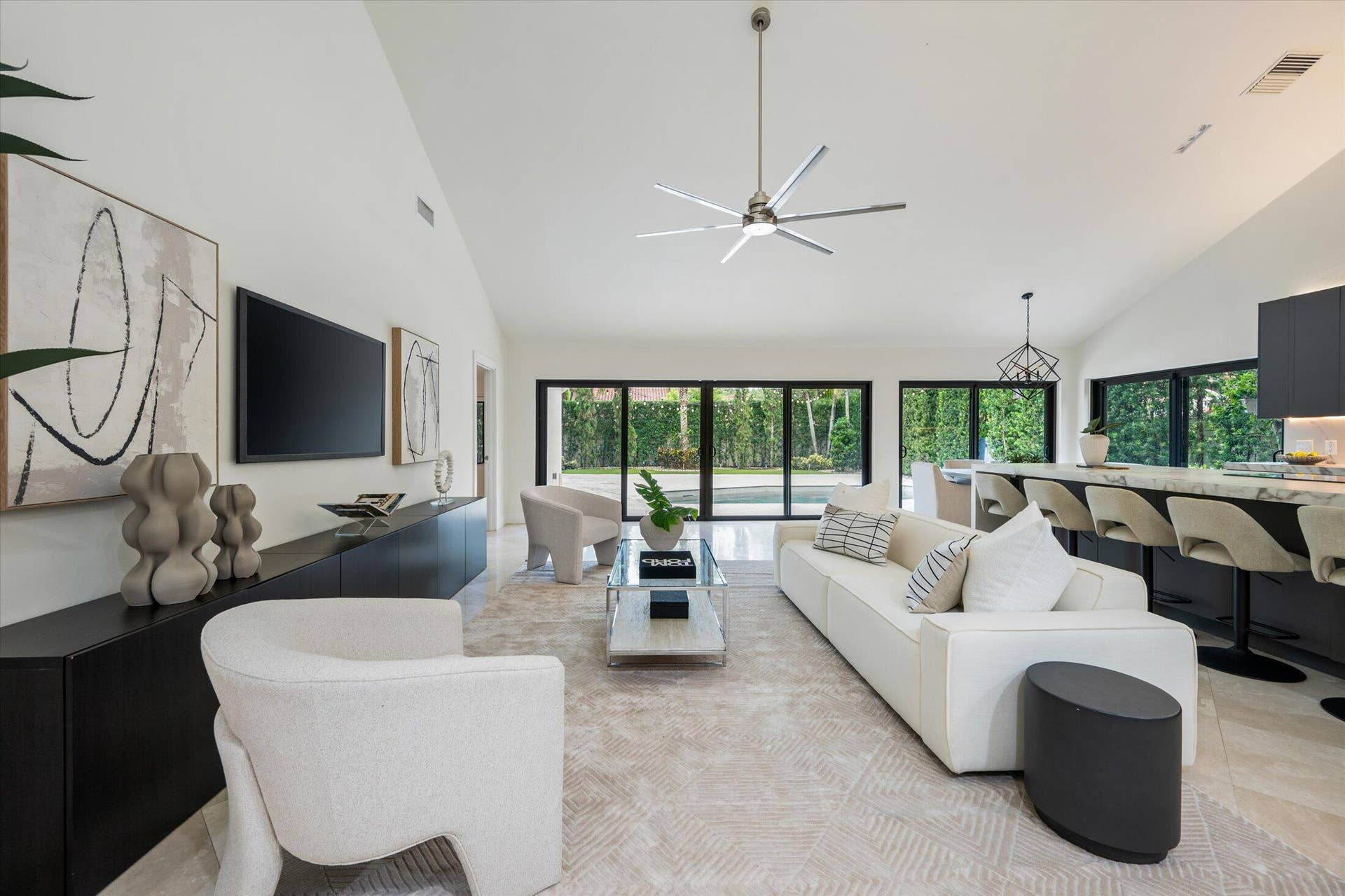 2890 ANTIETAM Lane, West Palm Beach, FL 33409 Vaulted ceilings, expansive glass doors, modern ceiling fan, built-in media console, and a kitchen island with seating