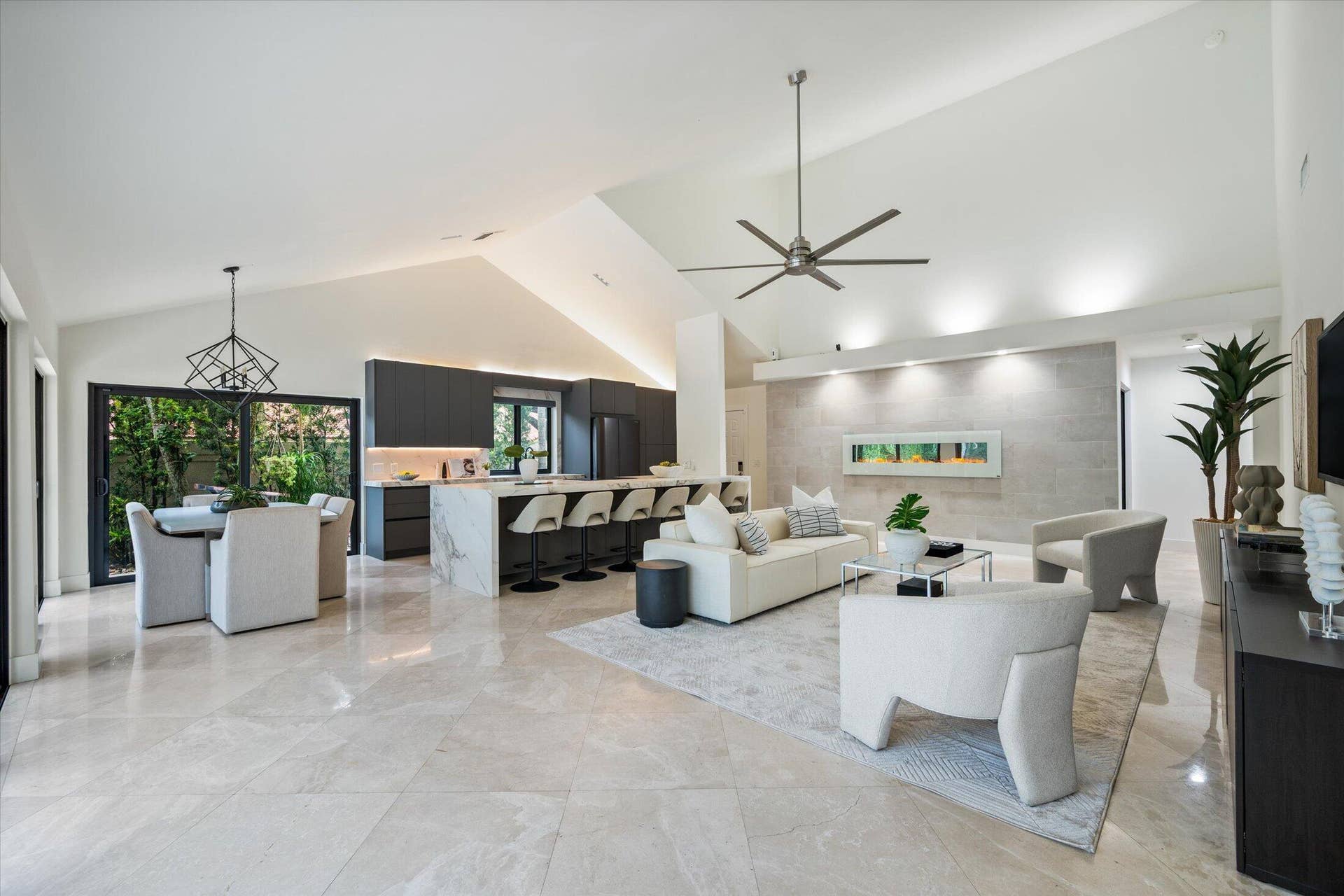 2890 ANTIETAM Lane, West Palm Beach, FL 33409 Vaulted ceilings, large format tile flooring, modern kitchen cabinetry, oversized kitchen island with waterfall countertop, and a wall-mounted linear fireplace
