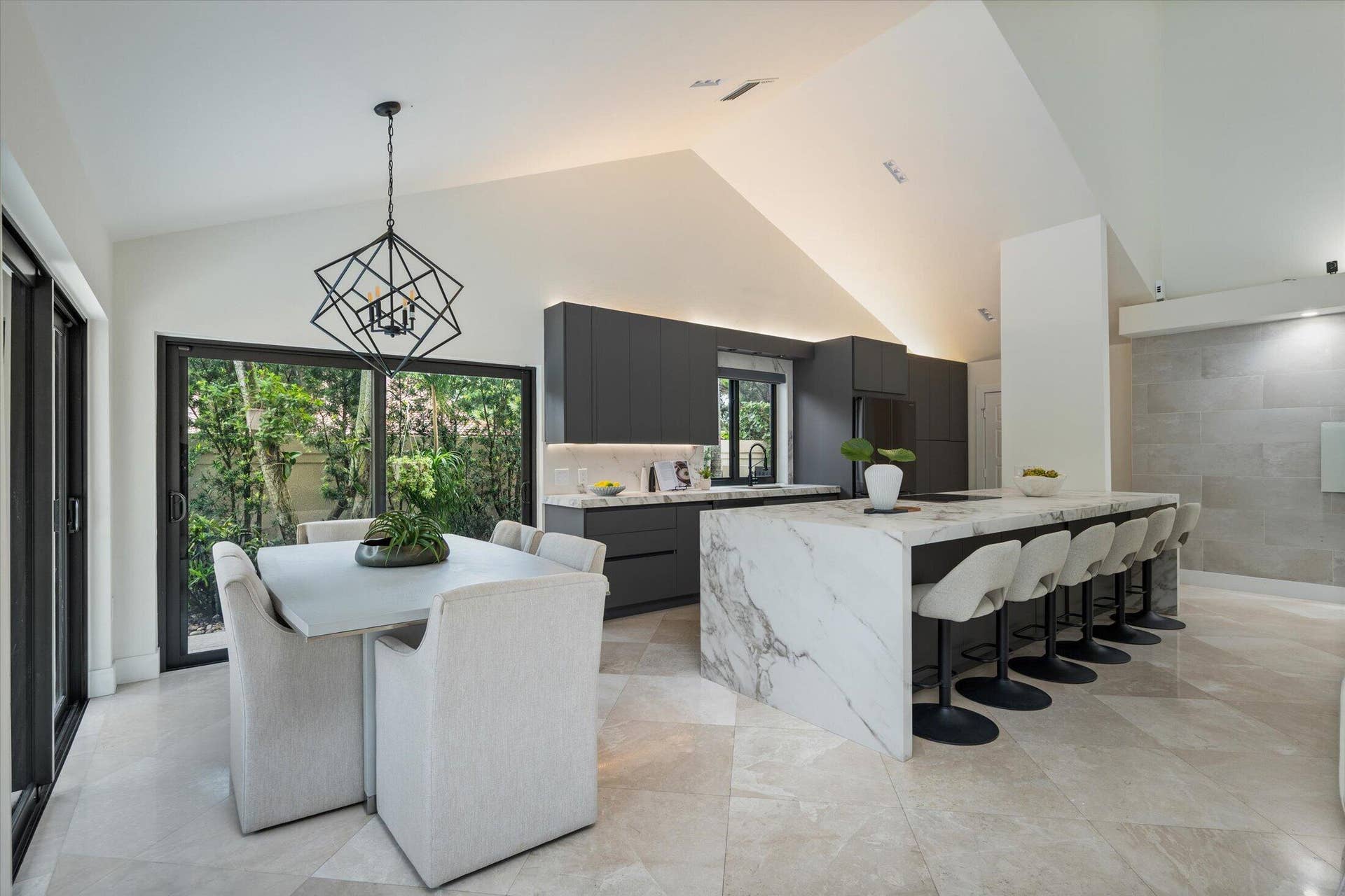 2890 ANTIETAM Lane, West Palm Beach, FL 33409 Vaulted ceilings with recessed lighting, large format floor tiling, a waterfall-edge island, dark flat-panel cabinetry, and sliding glass doors