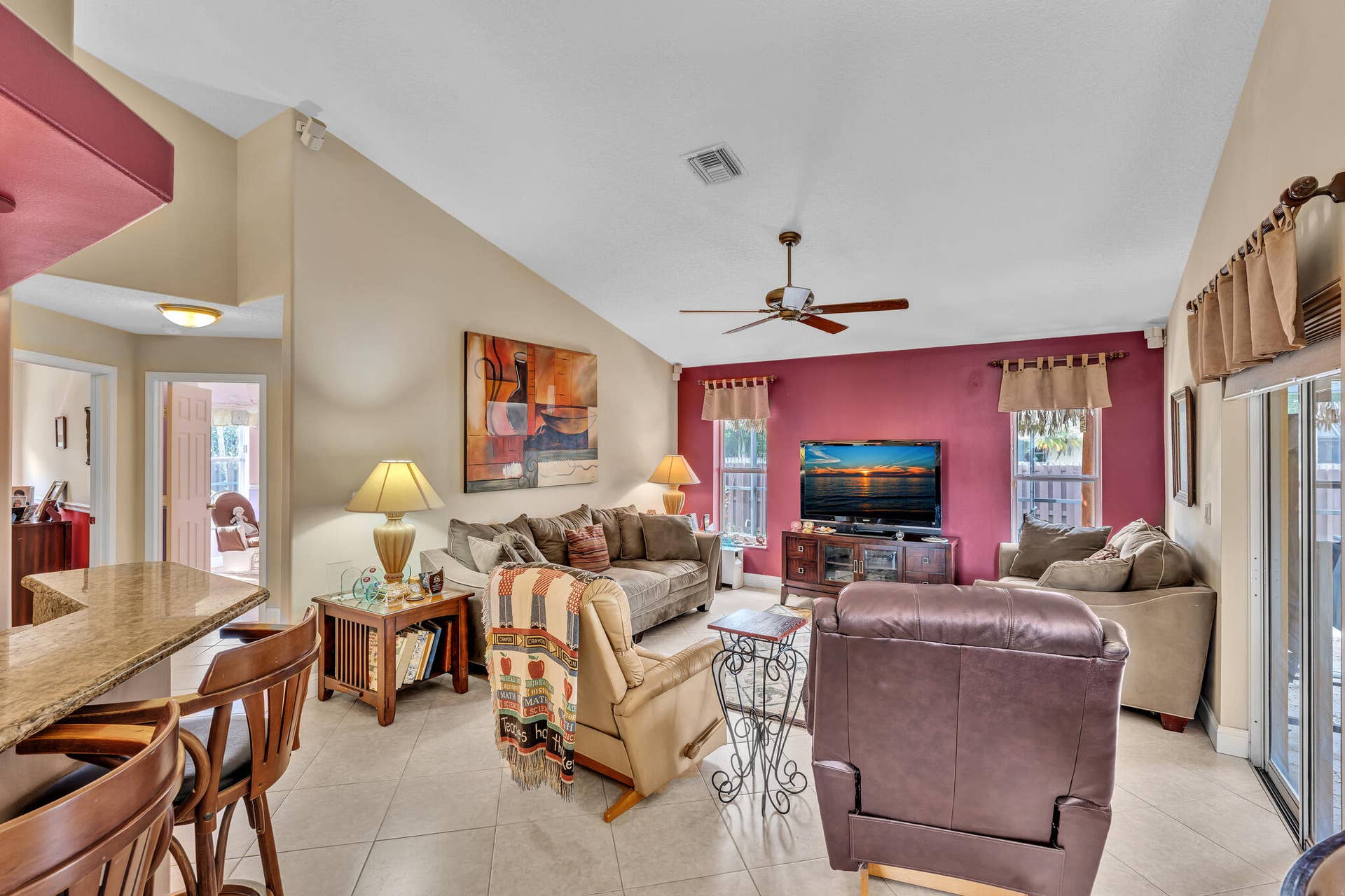 Vaulted ceilings, a ceiling fan, and tile flooring characterize this living space