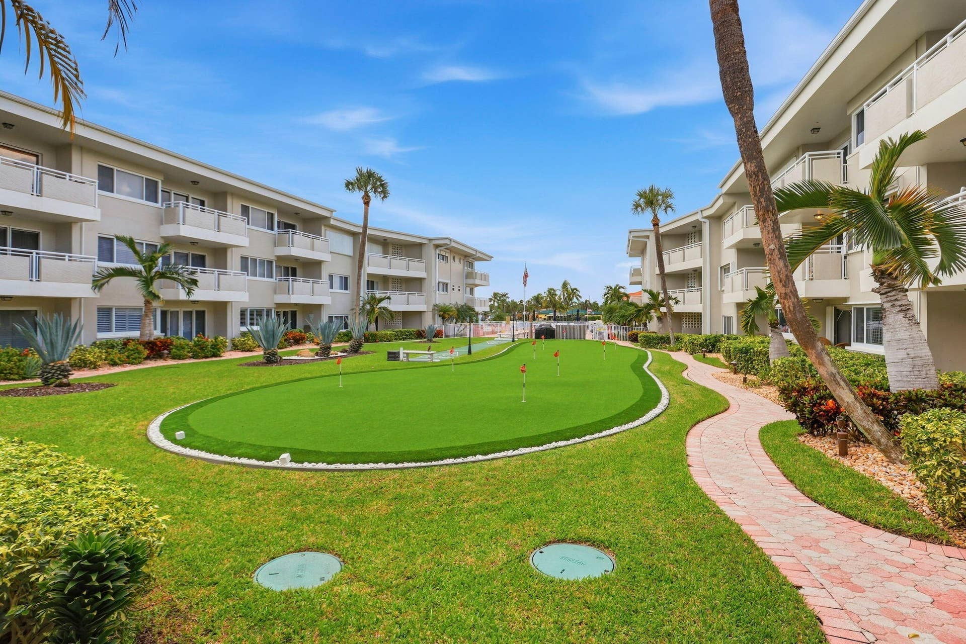1198 Hillsboro Mile, #210, Hillsboro Beach, FL 33062 Manicured grounds featuring a putting green, mature palm trees, and a winding brick pathway