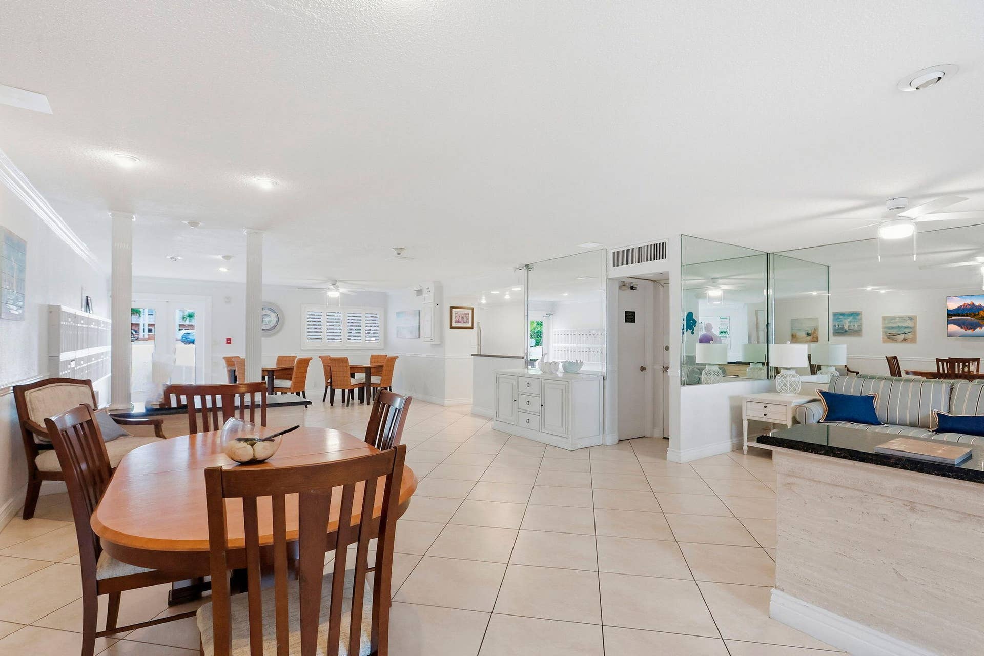 1198 Hillsboro Mile, #210, Hillsboro Beach, FL 33062 Open-concept interior featuring large format tile flooring, crown molding, multiple columns, and mirrored wall accents