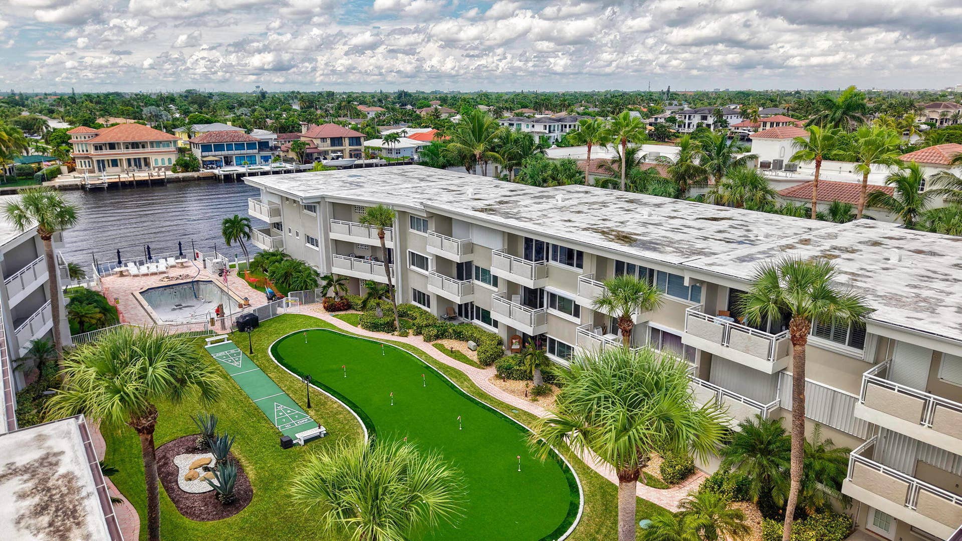 1198 Hillsboro Mile, #210, Hillsboro Beach, FL 33062 Waterfront condominium complex featuring multiple balconies, a putting green, a shuffleboard court, and an in-ground swimming pool