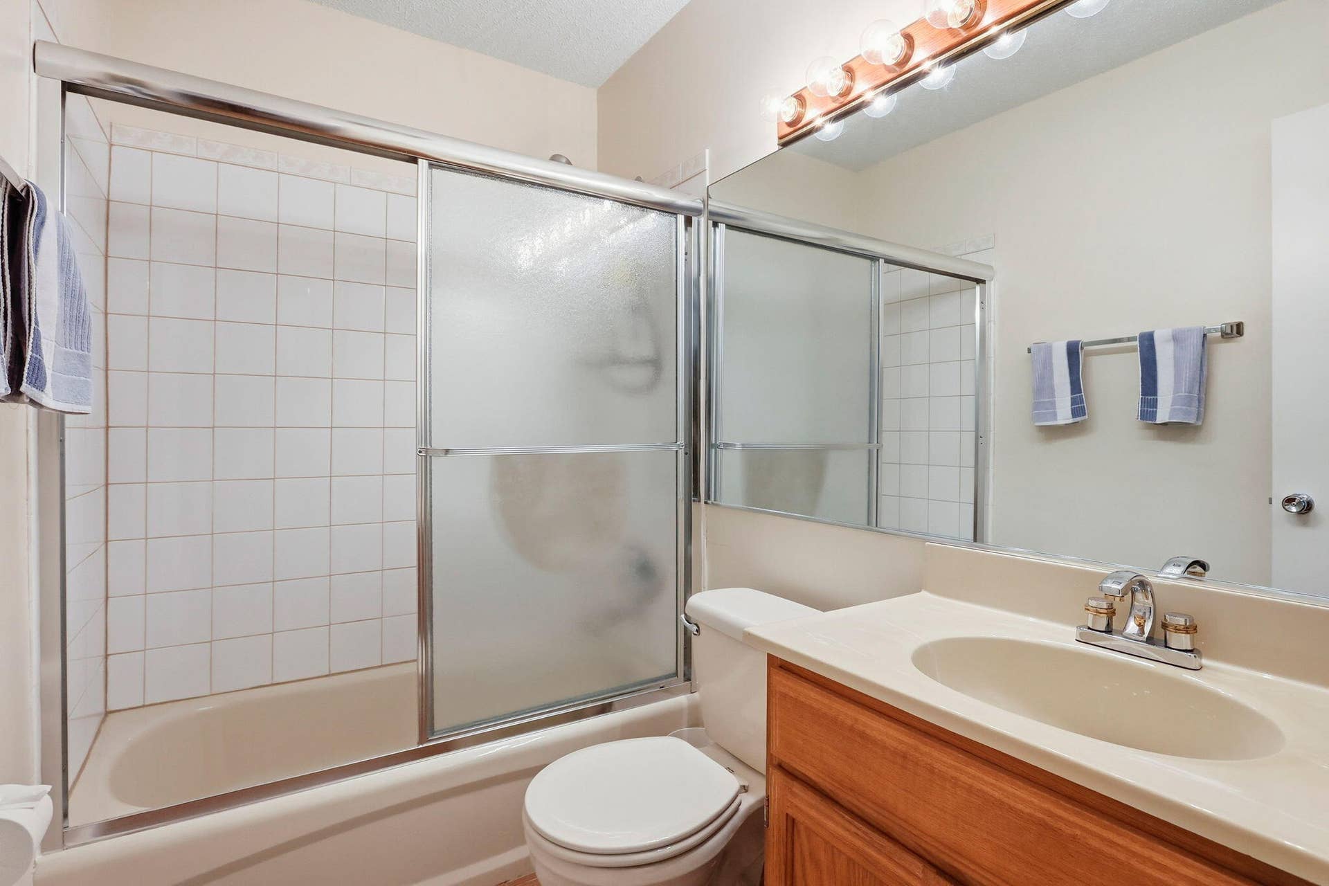 1198 Hillsboro Mile, #210, Hillsboro Beach, FL 33062 Tub-shower combination with sliding glass enclosure, white tile surround, and chrome fixtures