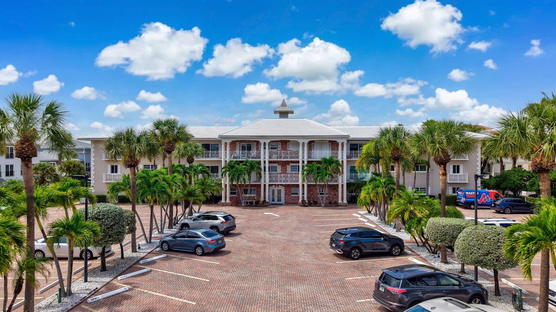 1198 Hillsboro Mile, #210, Hillsboro Beach, FL 33062 Multi-story residential building featuring a cupola, multiple balconies with white railings, and a red brick paver parking lot