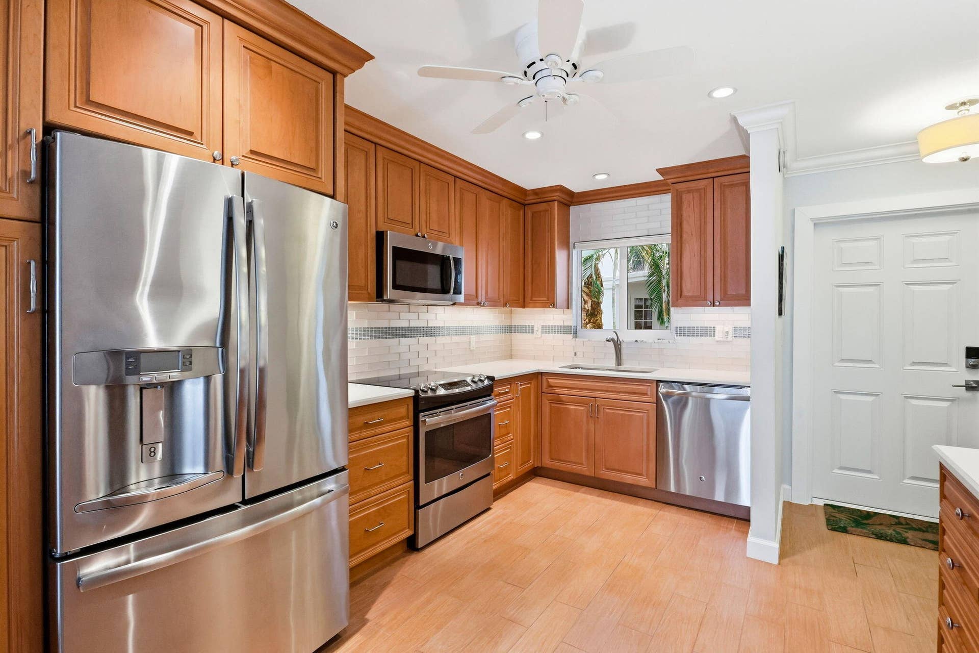 1198 Hillsboro Mile, #210, Hillsboro Beach, FL 33062 Kitchen featuring warm wood cabinetry, stainless steel appliances, a white tile backsplash, and light-toned flooring
