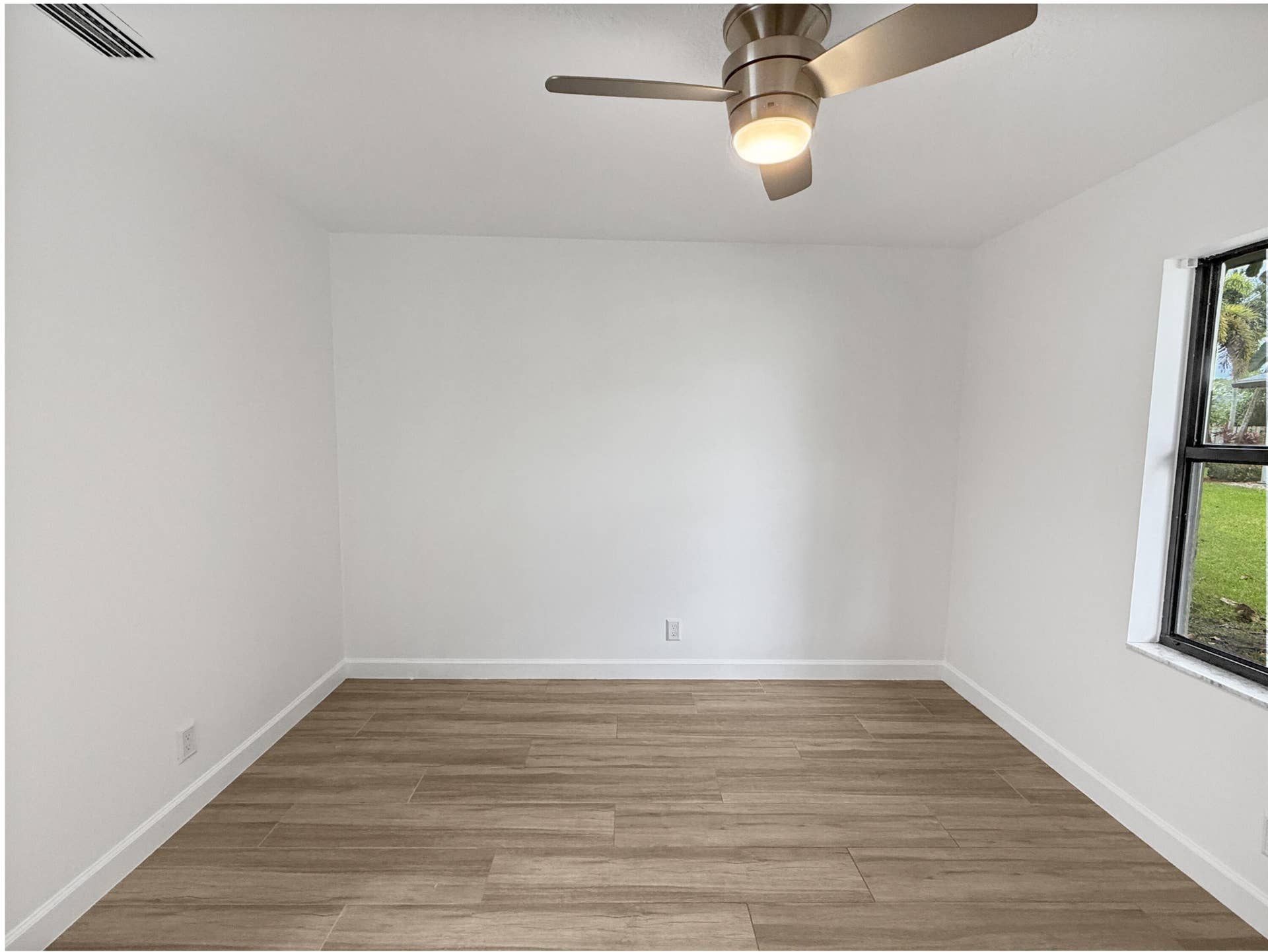Wood-finish tile flooring, white painted walls, and a ceiling fan with integrated lighting