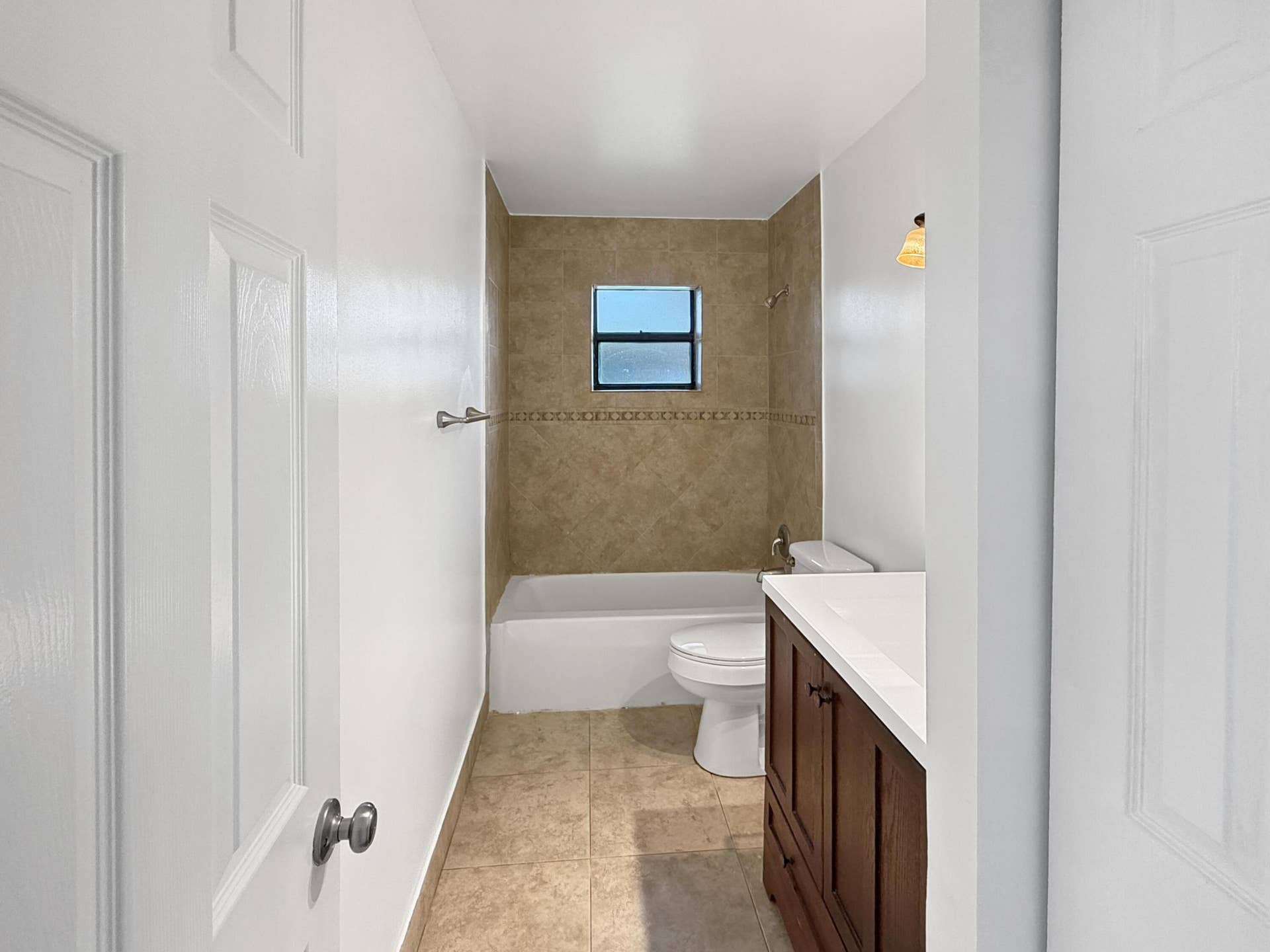 Tiled shower surround with decorative accent, built-in bathtub, and a window