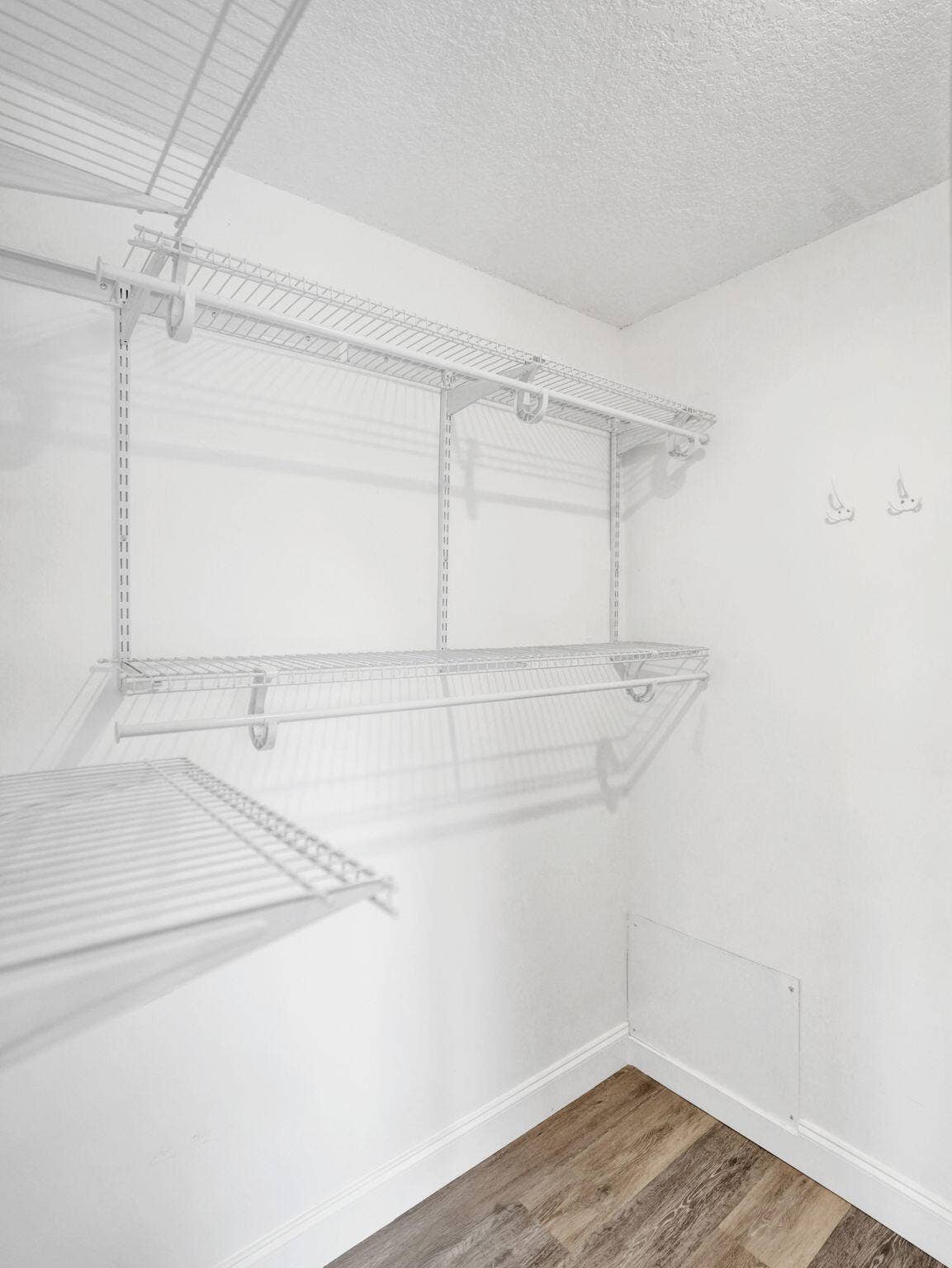 Integrated wire shelving system with multiple tiers, hanging rods, and wood-finish flooring
