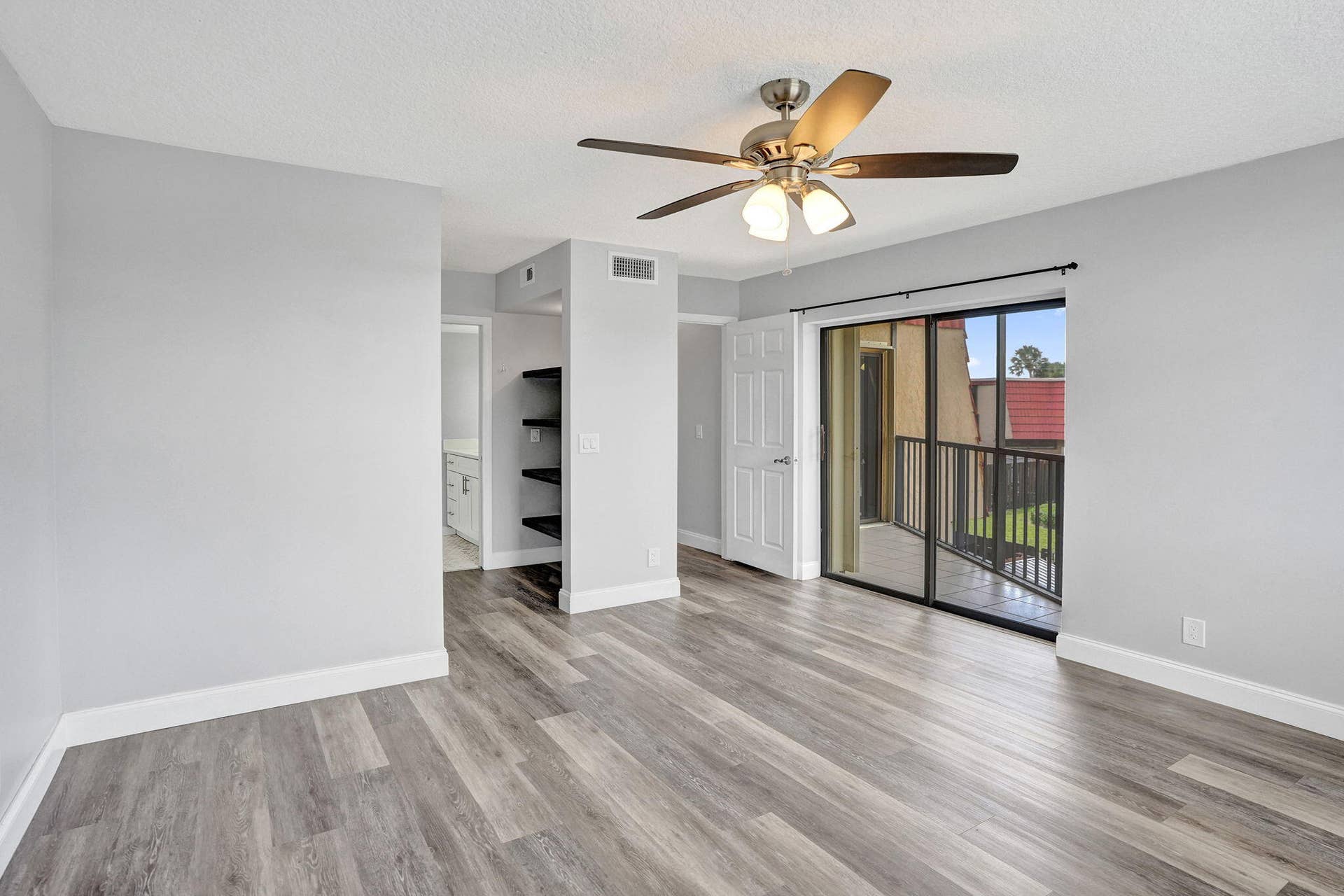Wood-finish flooring, ceiling fan and sliding door to a private balcony