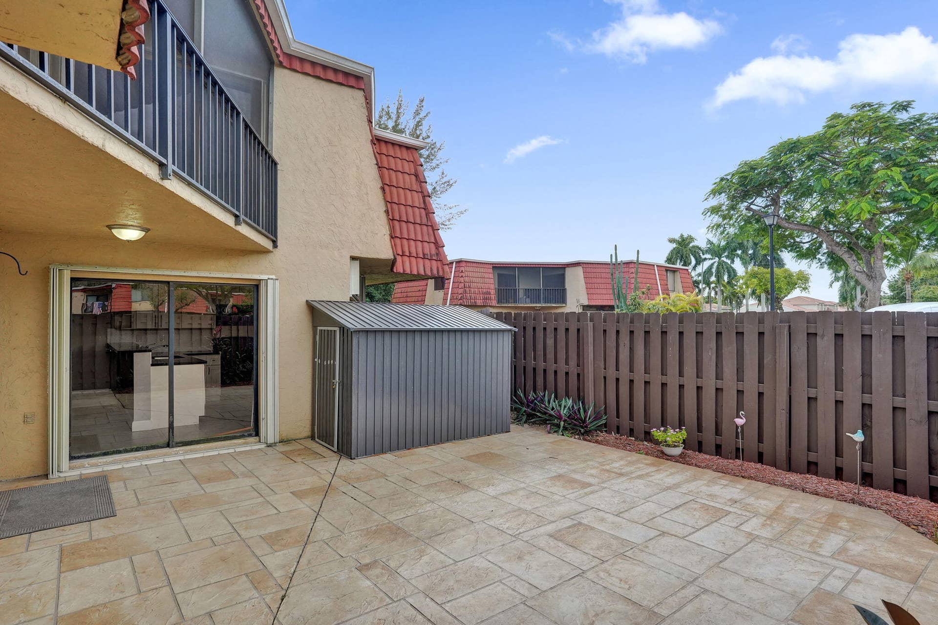 Private patio space featuring a privacy fence, exterior lighting, sliding glass door access, and a storage shed