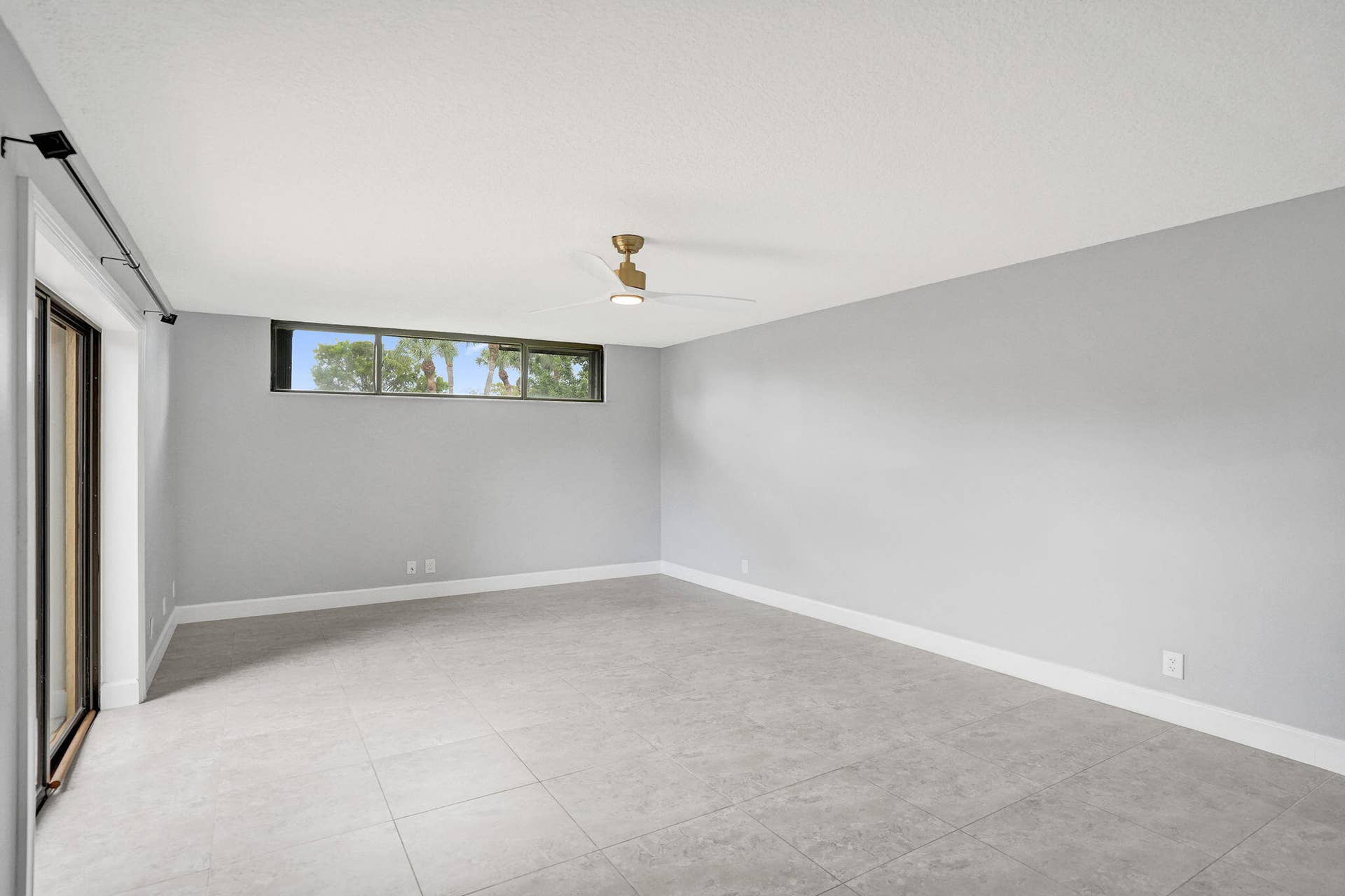 Spacious interior featuring light gray walls, large format tile flooring, and a sliding glass door