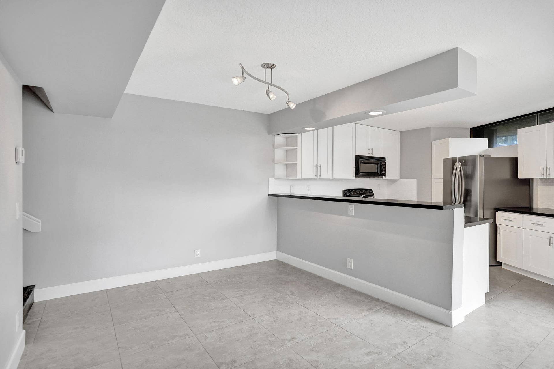 Open-concept living space with tile flooring and snack counter for convenience